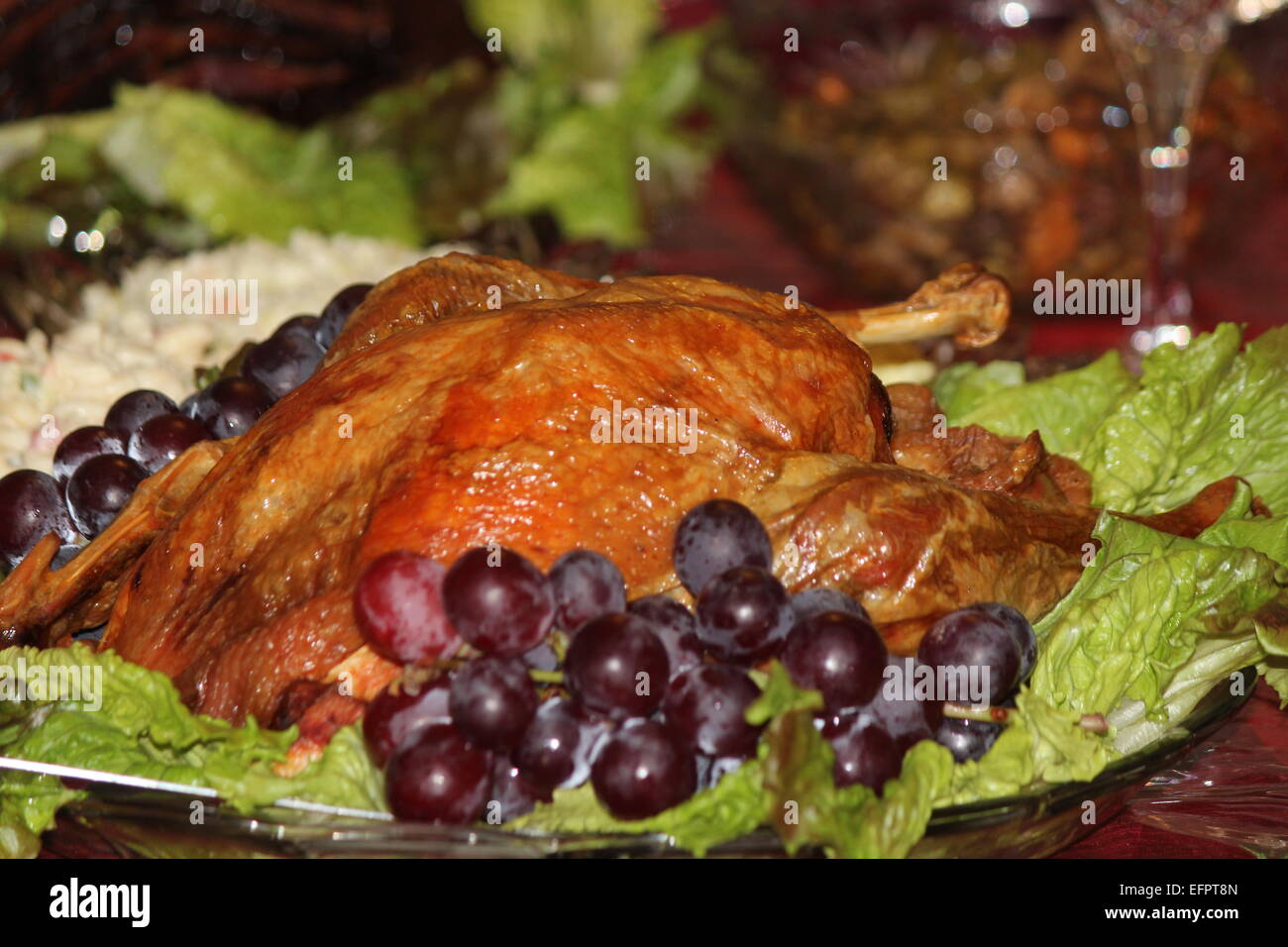 Gebratener Truthahn auf einem Tisch, auf ein Festessen vorbereitet, garniert mit Trauben. Stockfoto