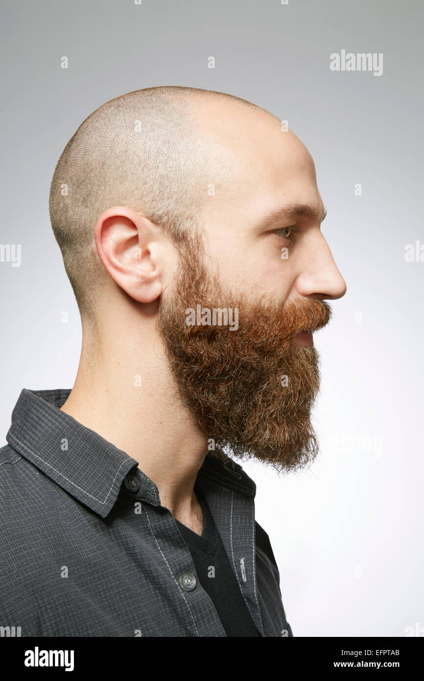 Profil von Studioportrait Mitte erwachsenen Mannes mit rasierten Haaren und verwilderten Bart Stockfoto