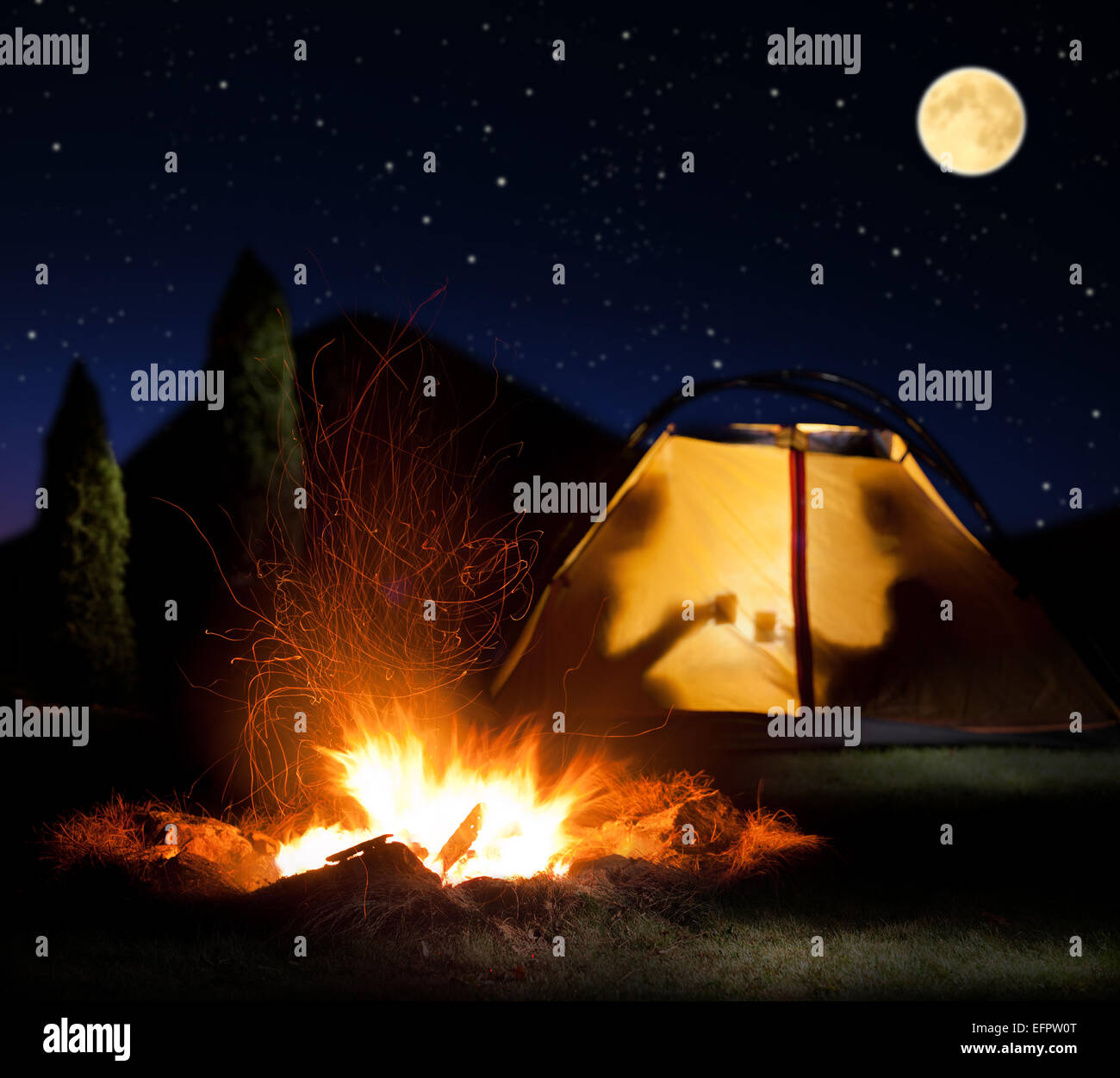 Camp leuchtet in der Nacht. Das Lagerfeuer in der Front als Symbol für Abenteuer und Romantik. Stockfoto