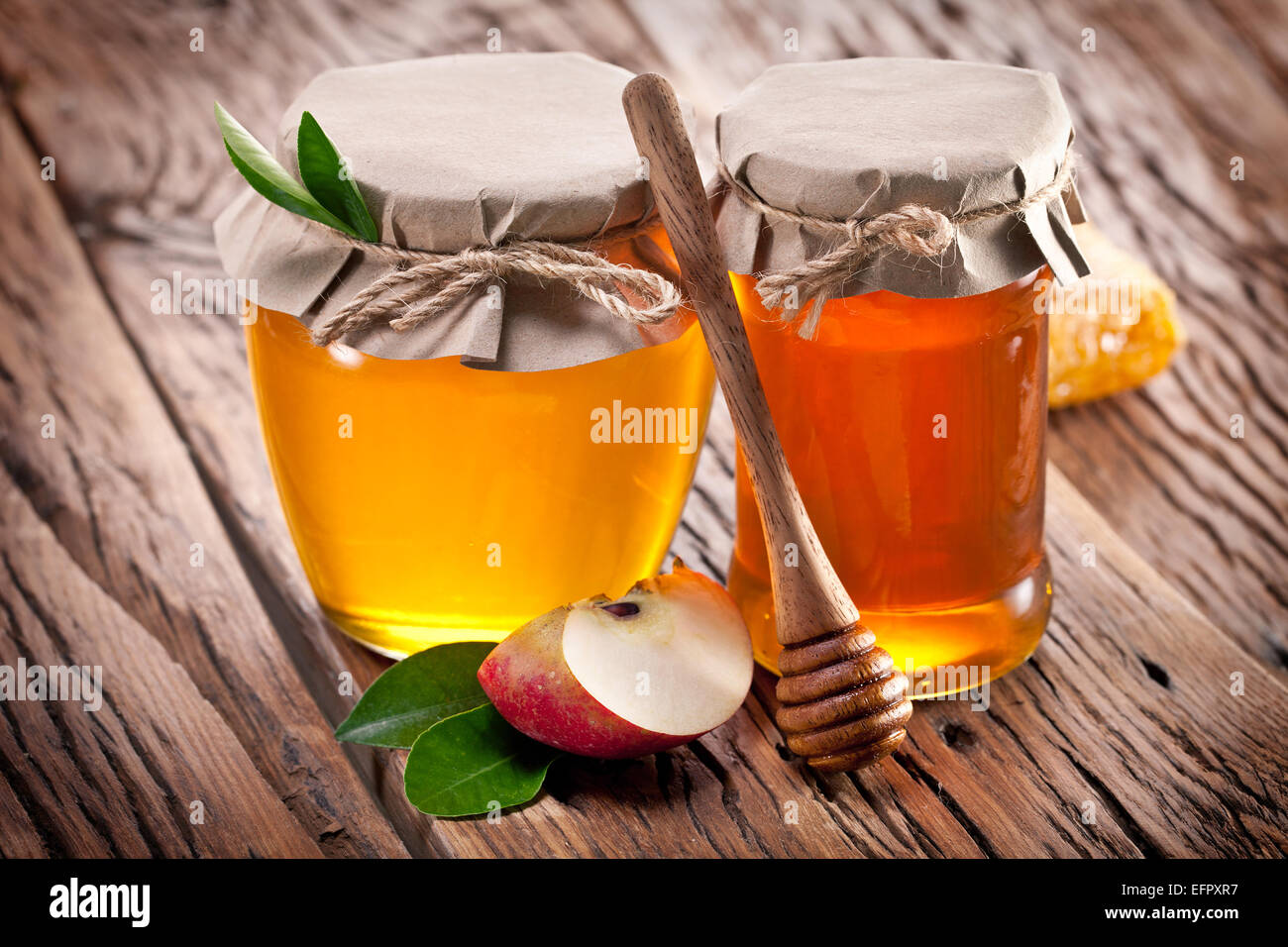 Glas-Dosen voller Honig und Apfel auf alten Holztisch. Stockfoto