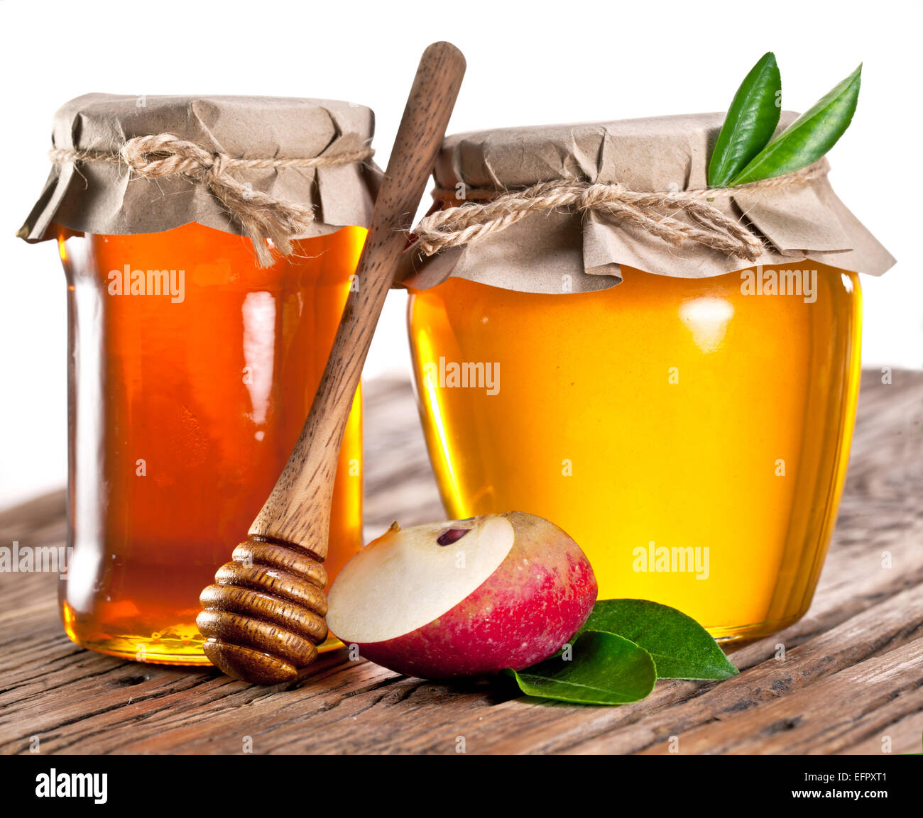 Glas-Dosen voller Honig und Äpfel auf alten Holztisch. Stockfoto