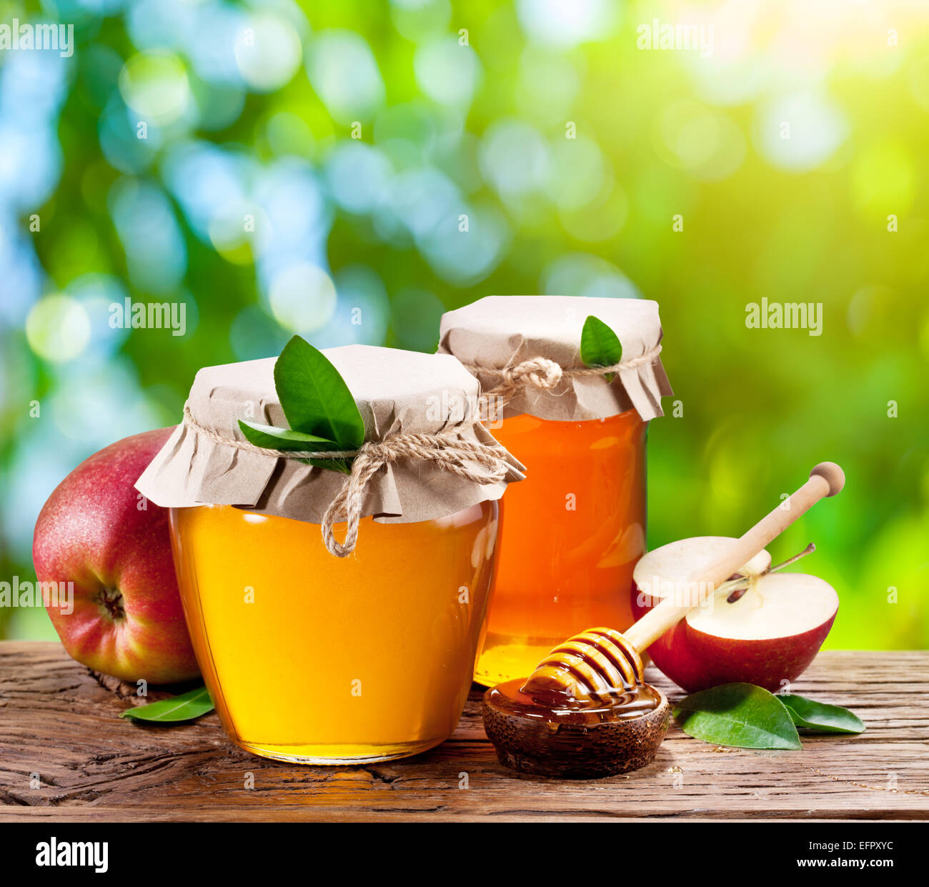 Glas-Dosen voller Honig, Äpfel und Kämme auf alten Holztisch im Garten. Stockfoto