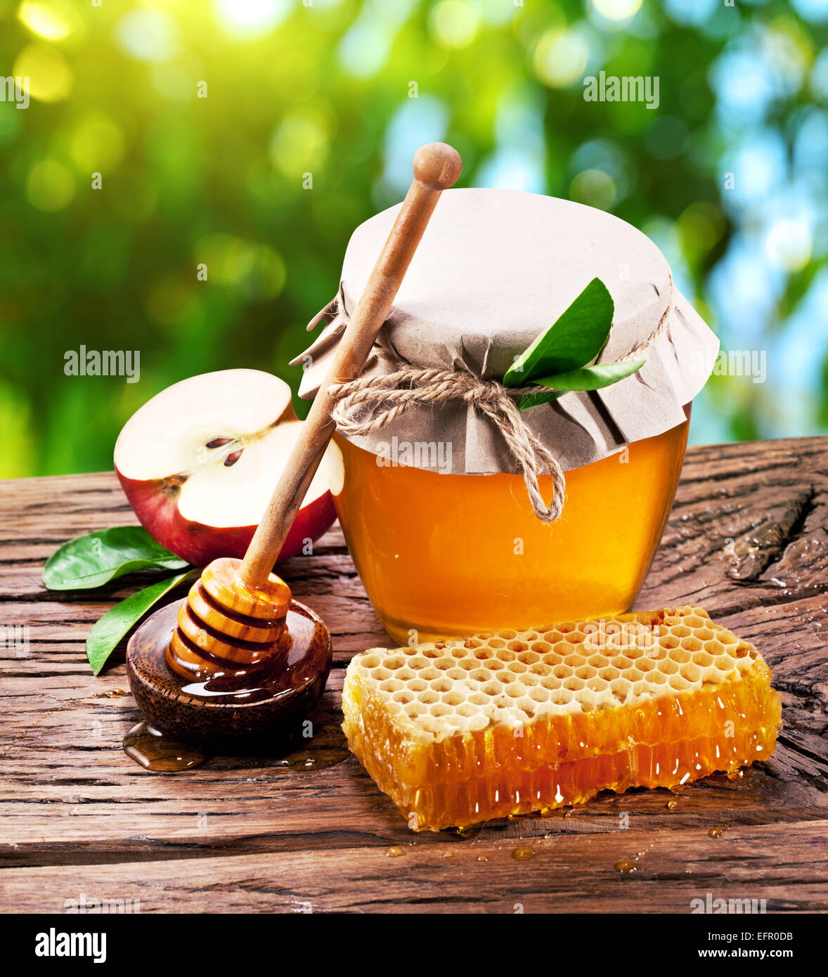 Glas-Dosen voller Honig, Äpfel und Waben auf alten Holztisch im Garten. Stockfoto