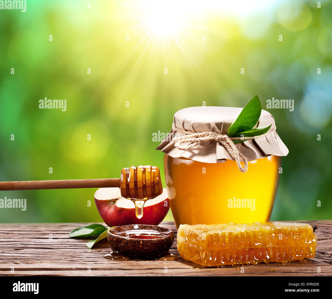 Glas kann voll von Honig, Apfel und Kämme auf Holztisch auf den Natur-Hintergrund. Stockfoto