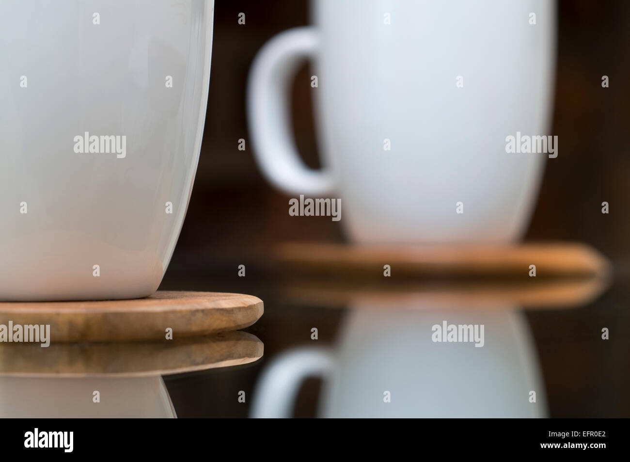 Reflektierte weiße Keramiktasse Holzachterbahnen auf Glastisch Stockfoto