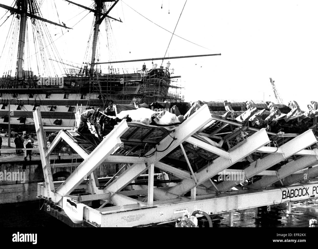 AJAXNETPHOTO. 8. DEZEMBER 1982. PORTSMOUTH, ENGLAND. -TUDOR KRIEGSSCHIFF KOMMT NACH HAUSE - DIE ÜBERRESTE VON HENRY VIII TUDOR KRIEGSSCHIFF MARY ROSE GEBORGEN AUS DEM SOLENT MEERESBODEN TRITT AM 10.12.82, DAS ALTE NR.3-DOCK IN PORTSMOUTH DOCKYARD WO ES WIRD DAUERHAFT BERUHEN. NELSONS FLAGGSCHIFF HMS VICTORY IST IN DEN ANGRENZENDEN NR.2.DOCK.  FOTO: SIMON BARNETT/AJAX REF: 821208 02 Stockfoto