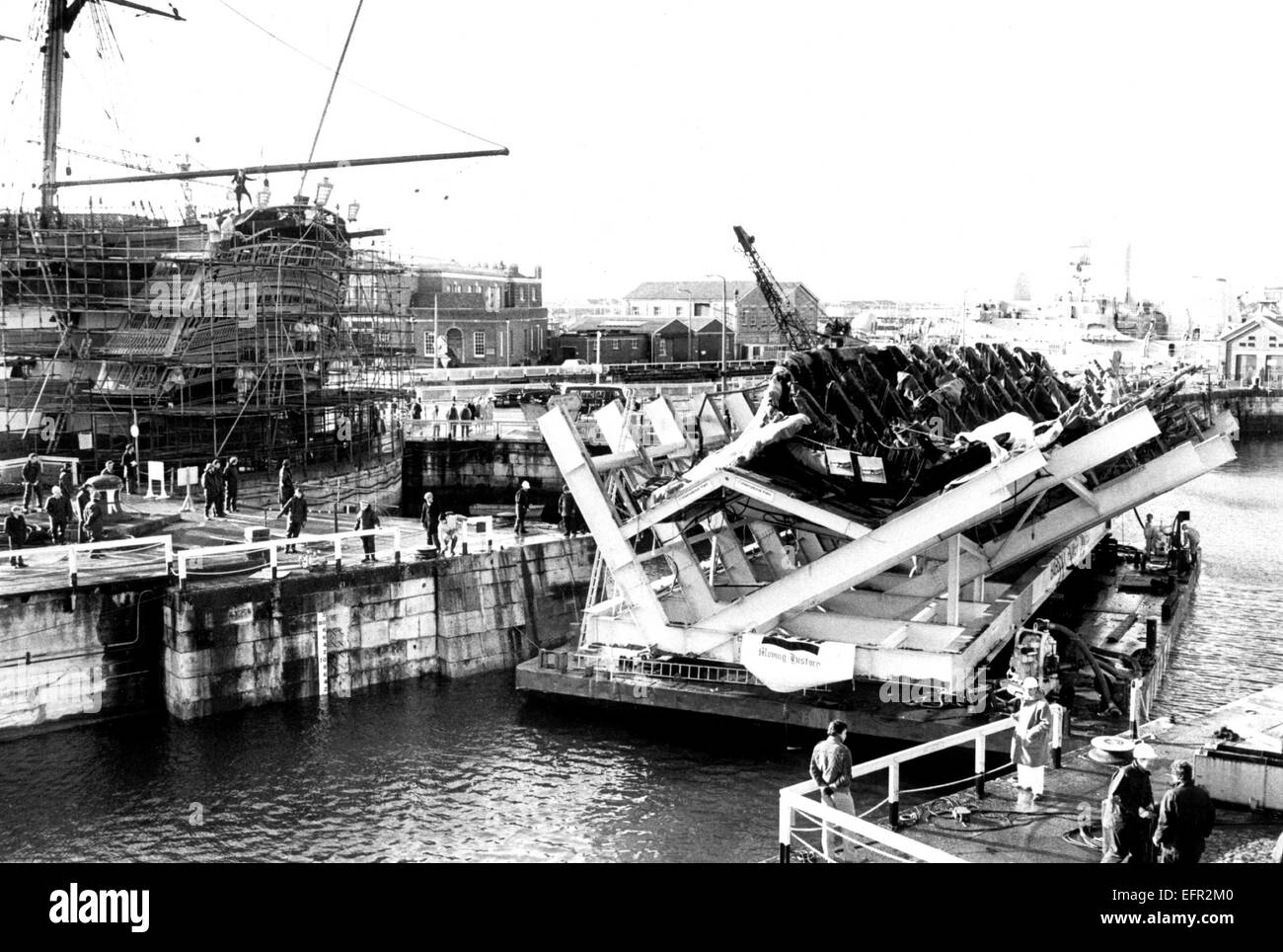 AJAXNETPHOTO. 8. DEZEMBER 1982. PORTSMOUTH, ENGLAND. -TUDOR KRIEGSSCHIFF KOMMT NACH HAUSE - DIE ÜBERRESTE VON HENRY VIII TUDOR KRIEGSSCHIFF MARY ROSE GEBORGEN AUS DEM SOLENT MEERESBODEN TRITT AM 10.12.82, DAS ALTE NR.3-DOCK IN PORTSMOUTH DOCKYARD WO ES WIRD DAUERHAFT BERUHEN. NELSONS FLAGGSCHIFF HMS VICTORY IST IN DEN ANGRENZENDEN NR.2.DOCK.  FOTO: SIMON BARNETT/AJAX REF: 821208 03 Stockfoto