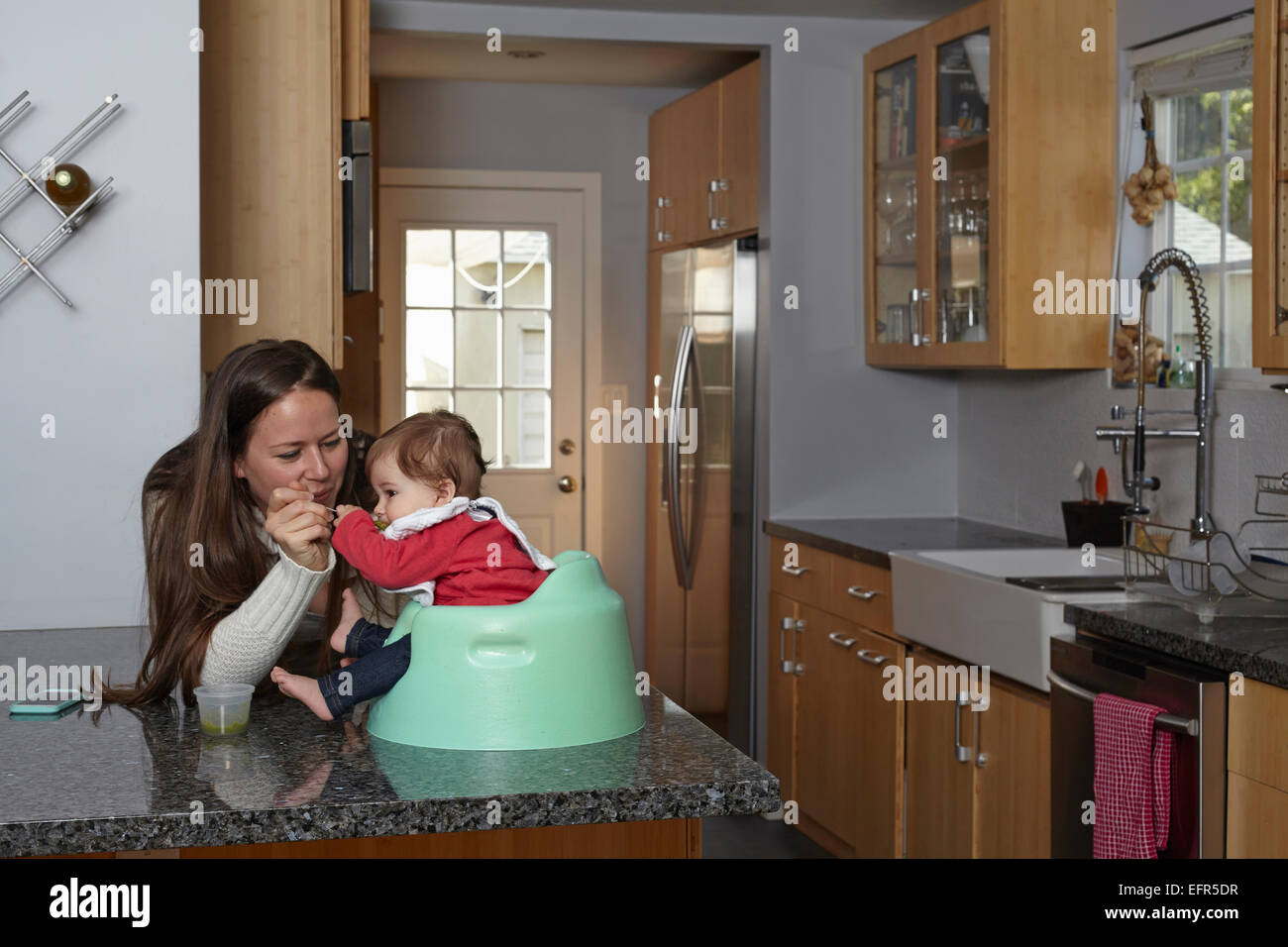 Mutter Fütterung Babymädchen auf der Küchentheke Stockfoto