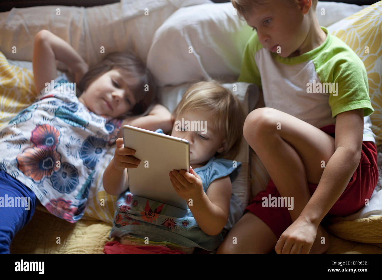 Drei kleine Kinder entspannend auf Bett mit digital-Tablette Stockfoto