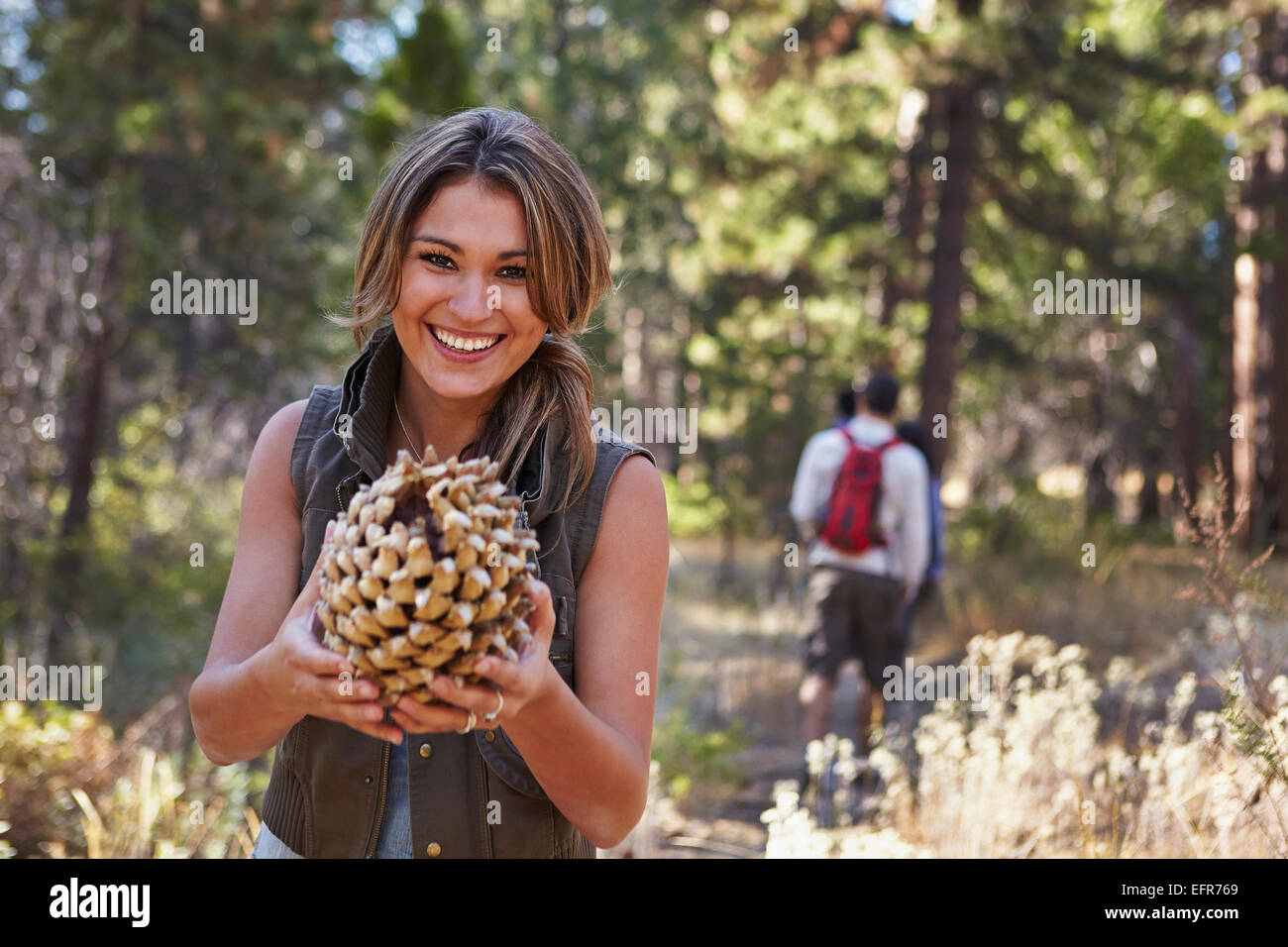 Porträt der jungen Frau im Wald mit großer Tannenzapfen, Los Angeles, Kalifornien, USA Stockfoto