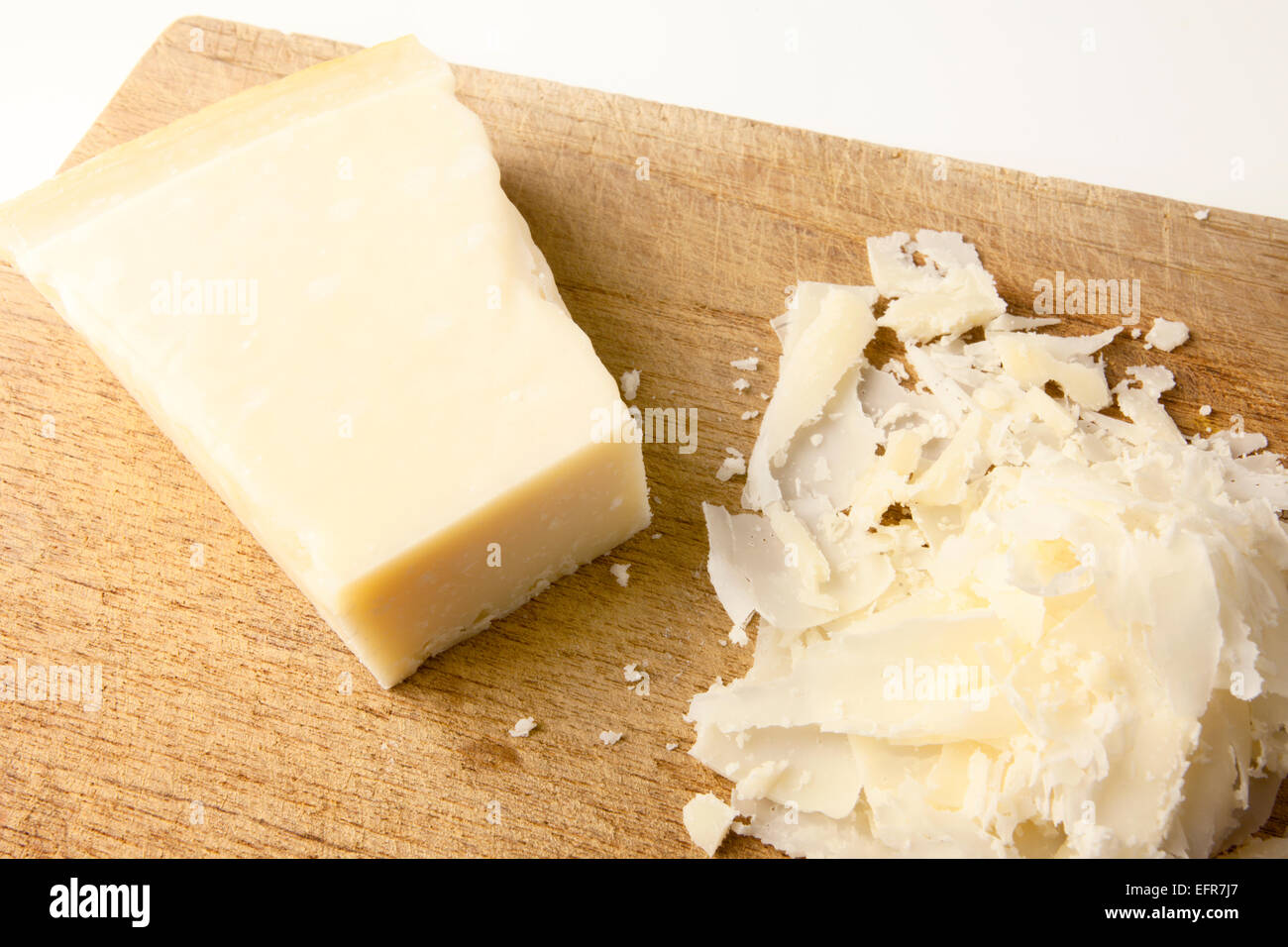 Block mit Parmesan und gehobeltem Parmesan auf einem Holzbrett Stockfoto
