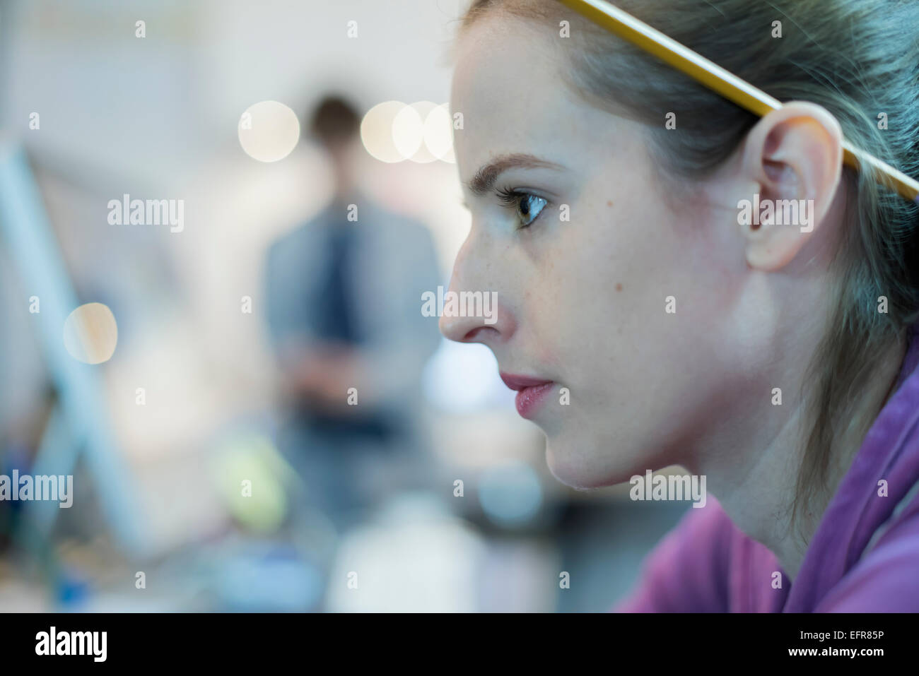 Eine junge Frau mit einem Bleistift hinter ihr Ohr an eine Computer-Werkstatt. Stockfoto