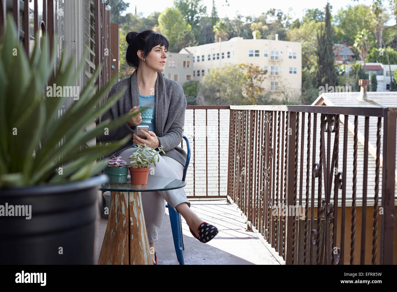 Frau mit Smartphone auf Balkon Stockfoto