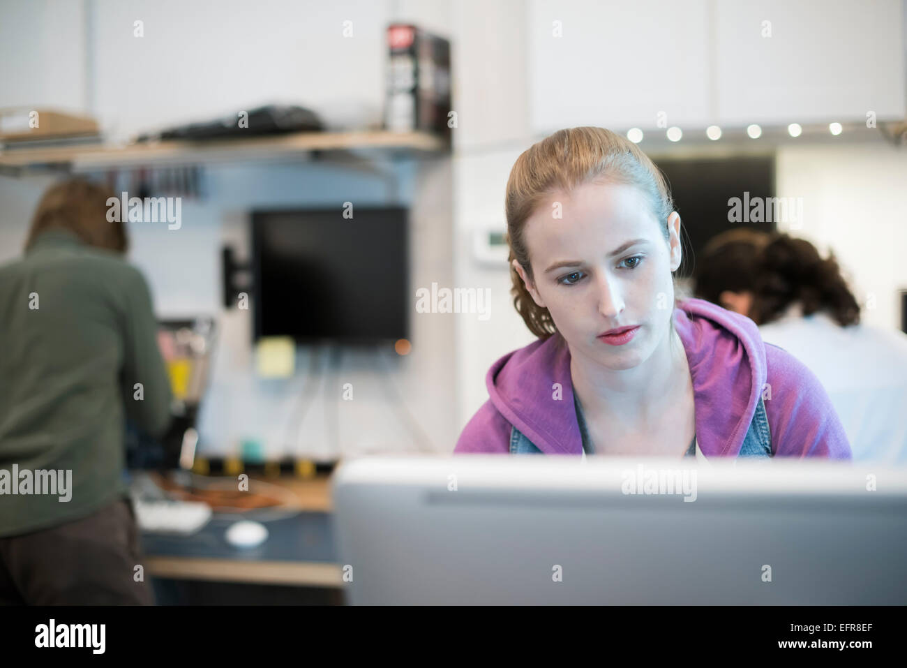Computer-Werkstatt. Eine Frau an einem Computer runzelt die Stirn auf den Bildschirm. Stockfoto