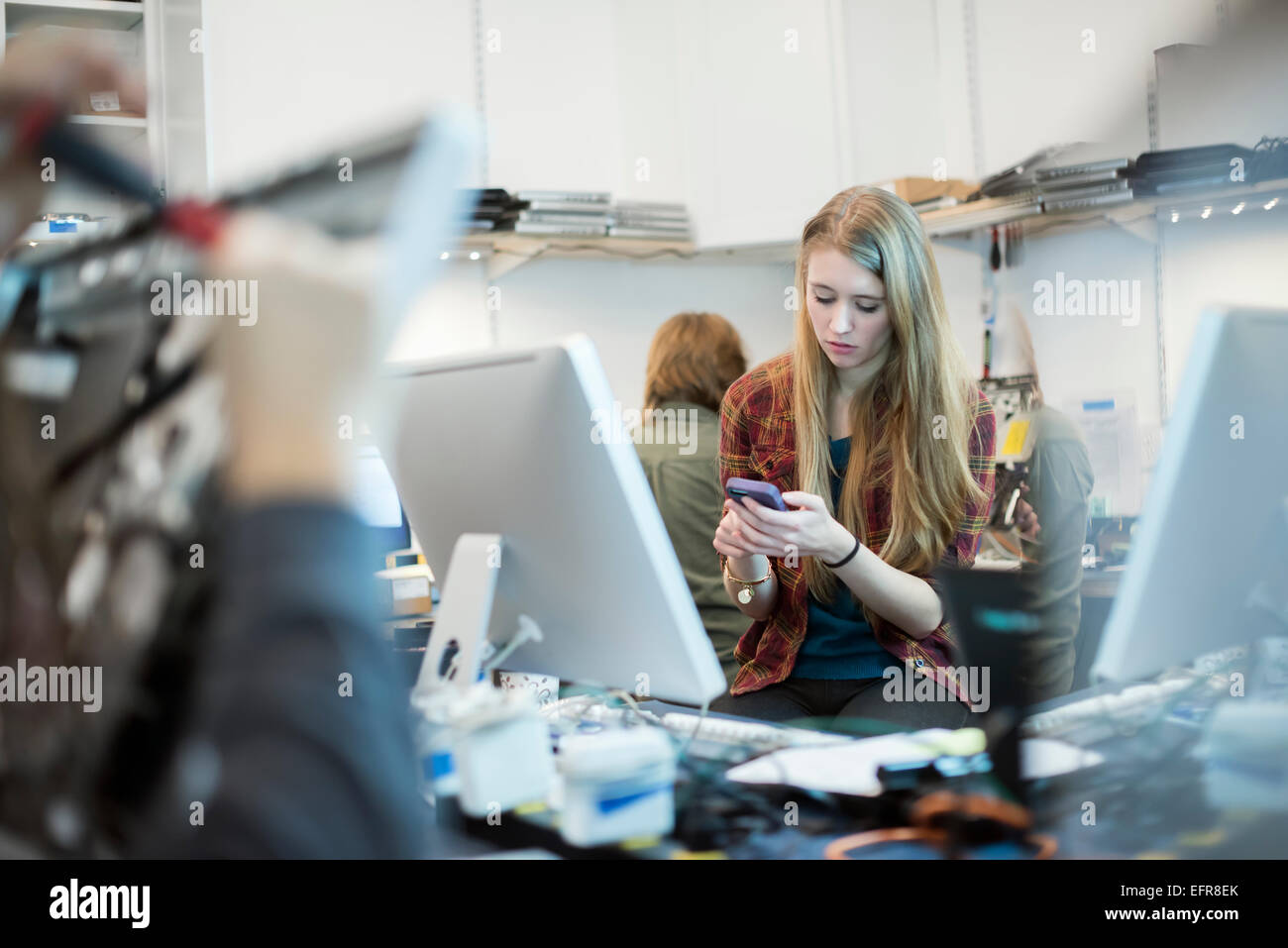 Computer-Werkstatt. Eine Frau mit einem Smartphone.  Menschen arbeiten am Computer-Reparaturen. Stockfoto