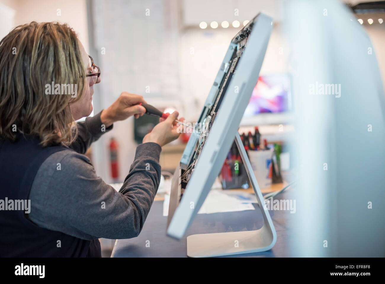 Computer-Werkstatt. Ein Mann arbeitet an einem Computer-Monitor, es zu reparieren. Stockfoto