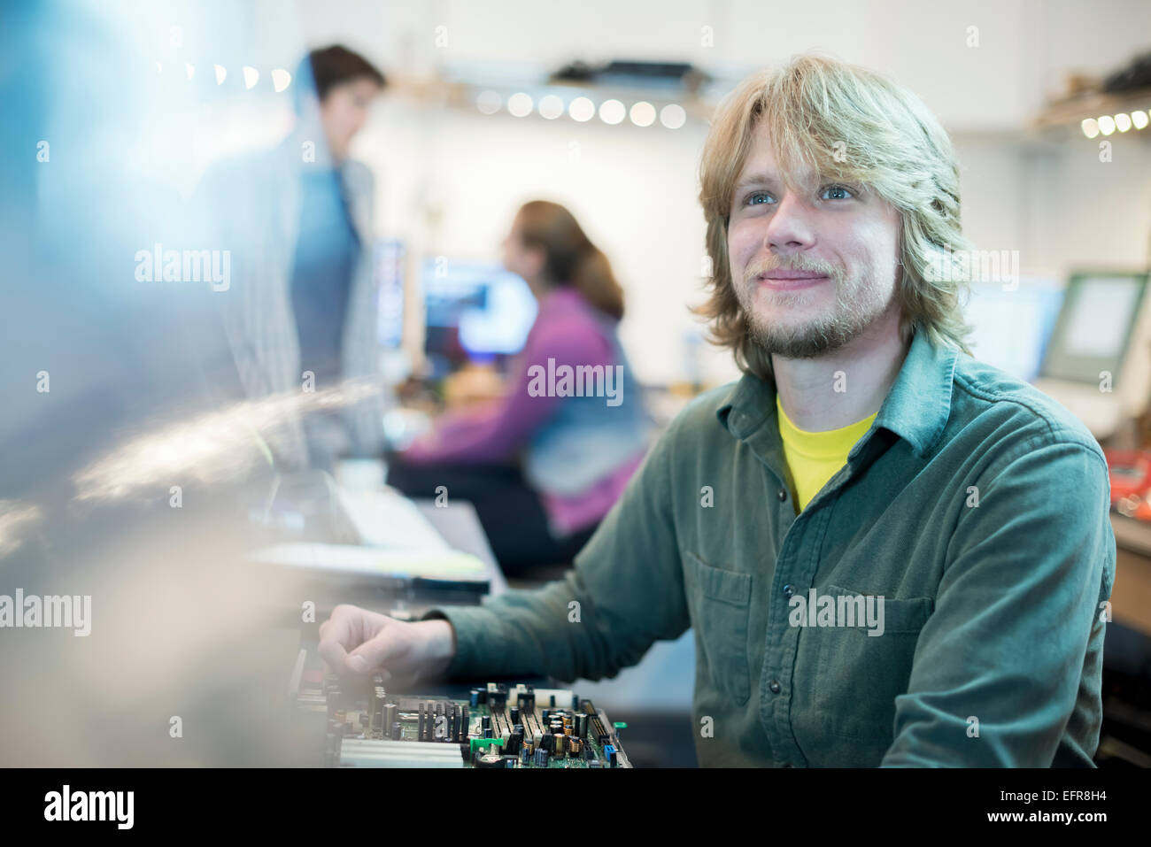 Ein junger Mann und zwei Kollegen in einem Computer-Shop. Stockfoto