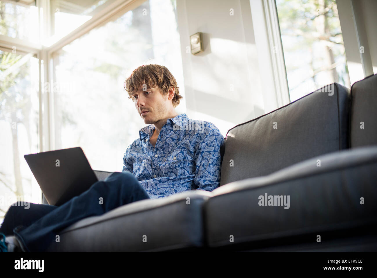 Niedrigen Winkel Blick eines Mannes auf einem Sofa, Blick auf seinem Laptop sitzt. Stockfoto