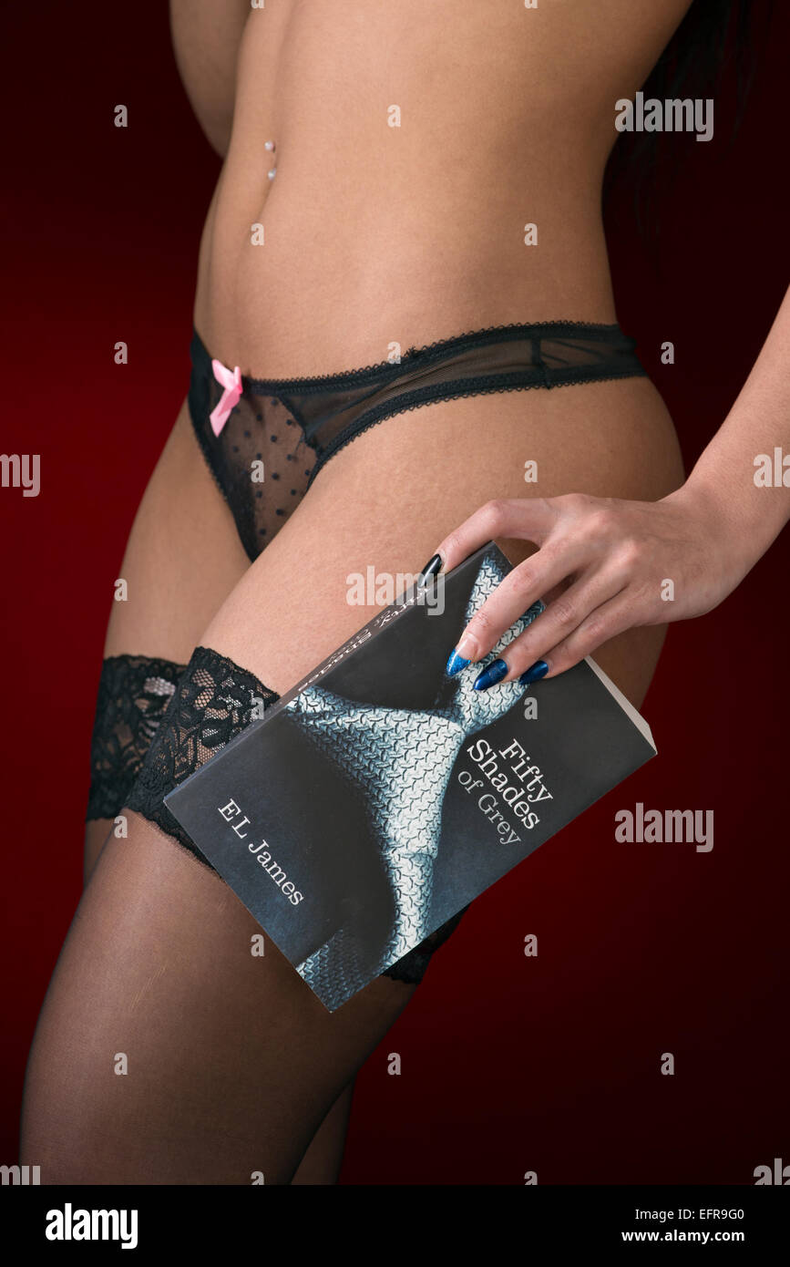 Ein Mädchen in sexy schwarzen Unterwäsche hält Handschellen & eine Kopie  von 50 Shades of Grey, vor einem roten Hintergrund Stockfotografie - Alamy