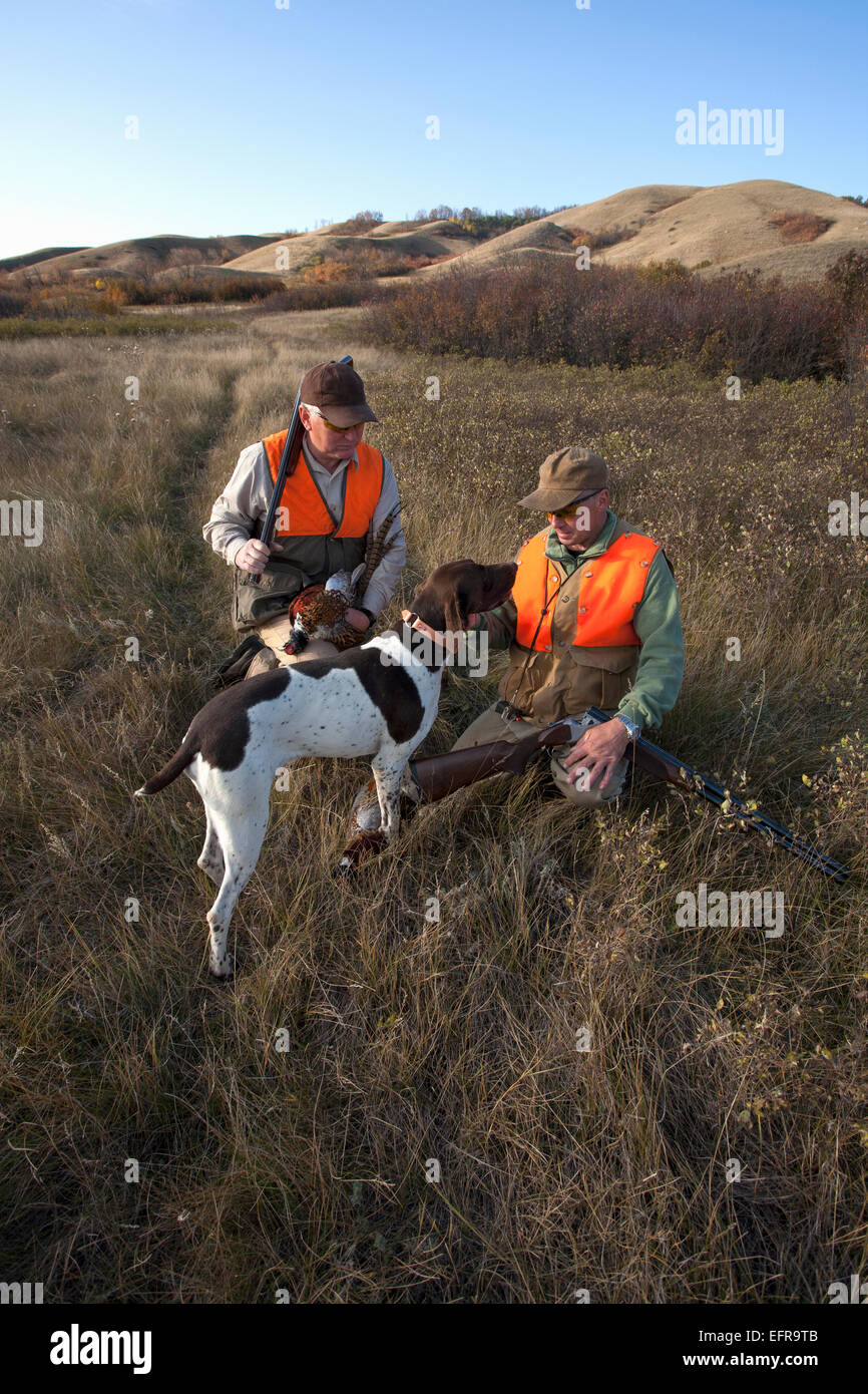 Zwei Männer, Vogel Jäger mit Schrotflinten, Tragetasche für den Tag Tote Vögel und einem Spaniel Hund. Stockfoto
