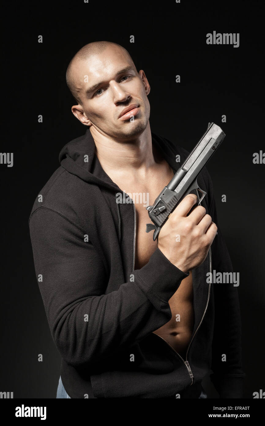 männliche Gangster mit einer Pistole auf schwarzem Hintergrund isoliert Stockfoto