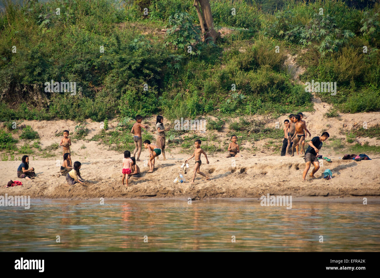 Horizontale Ansicht von einer Gruppe von Kindern spielen und entspannen an den Ufern des Mekong-Flusses. Stockfoto