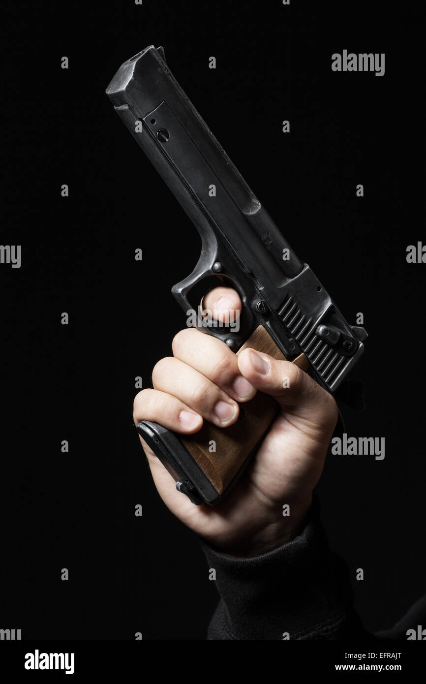 männliche Hand mit Gewehr auf schwarzem Hintergrund isoliert Stockfoto