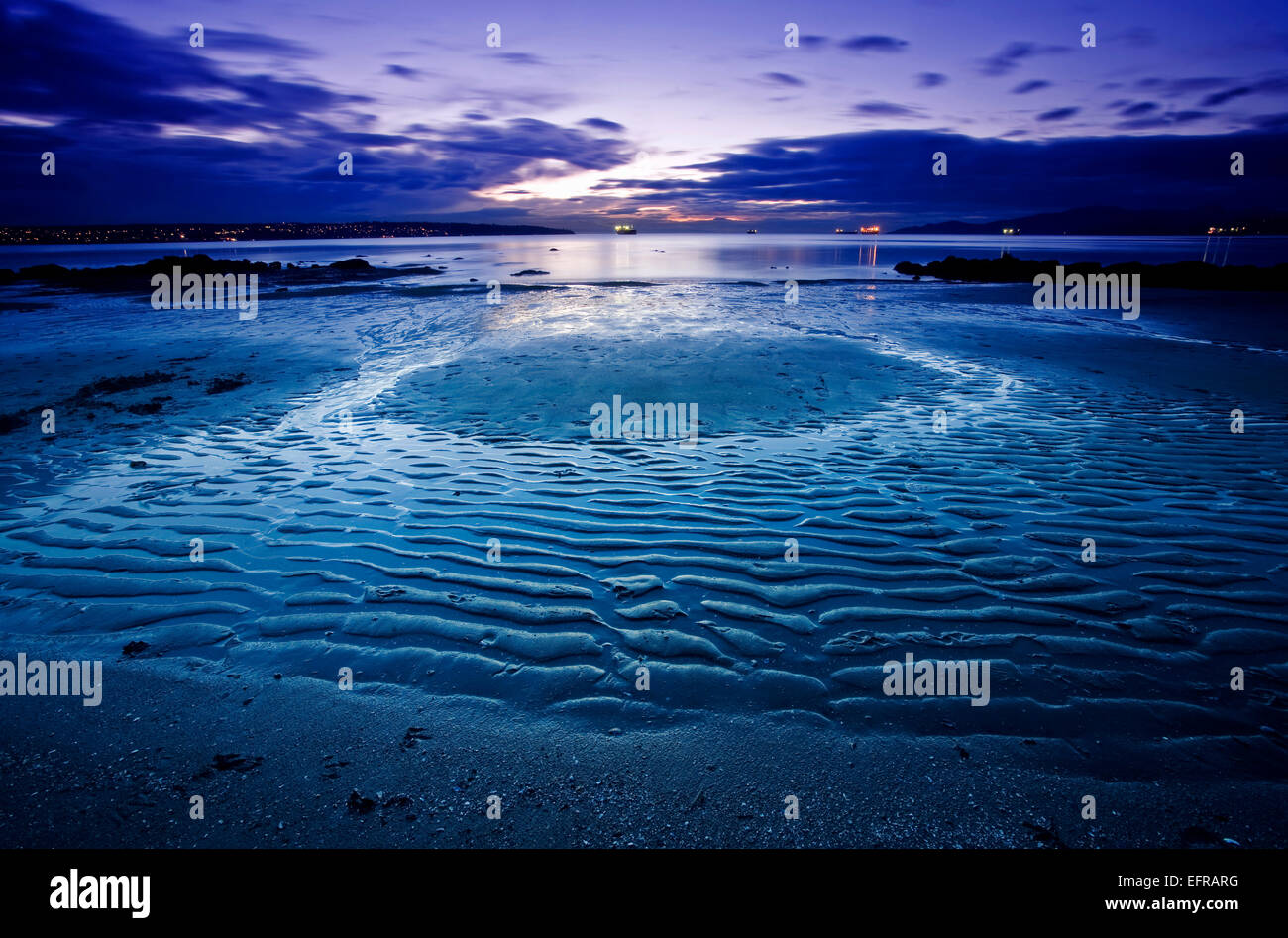 Ein Strand bei Ebbe unter einer dunkler werdenden Himmel. Ripple Muster auf dem Sand. Stockfoto