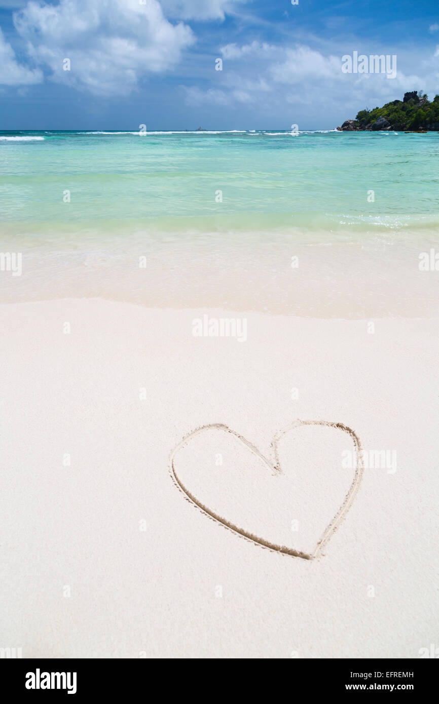 Die Form eines Herzens in den Sand von einem sauberen weißen Strand mit türkisblauem Wasser Stockfoto