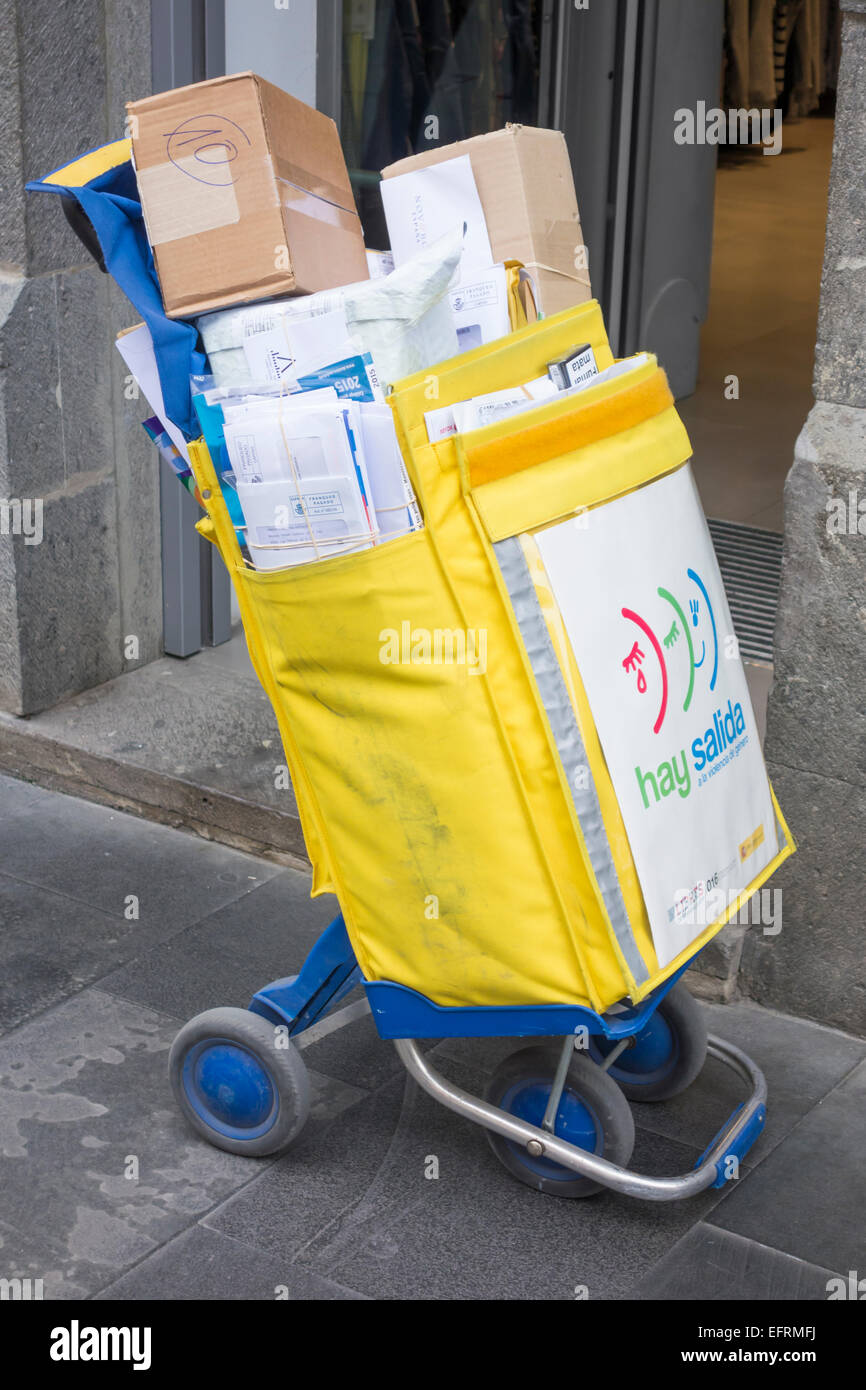 Spanische Postarbeiter Blätter Trolley/Tasche außen Shop während der Zustellung. Stockfoto