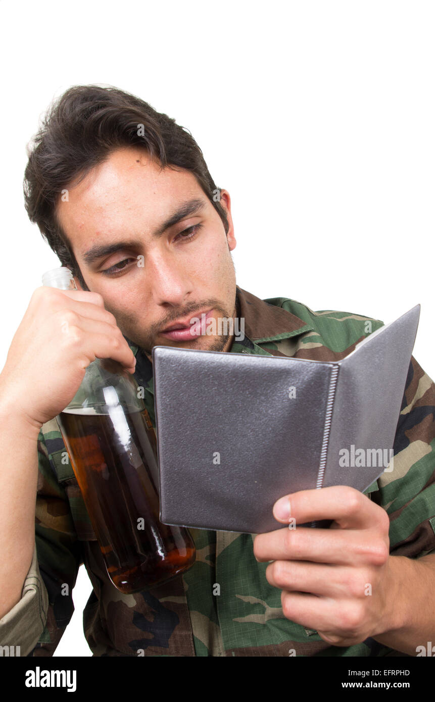 verzweifelte militärische Soldat Veteran hält eine Flasche und mit Blick auf Fotos ptsd Stockfoto