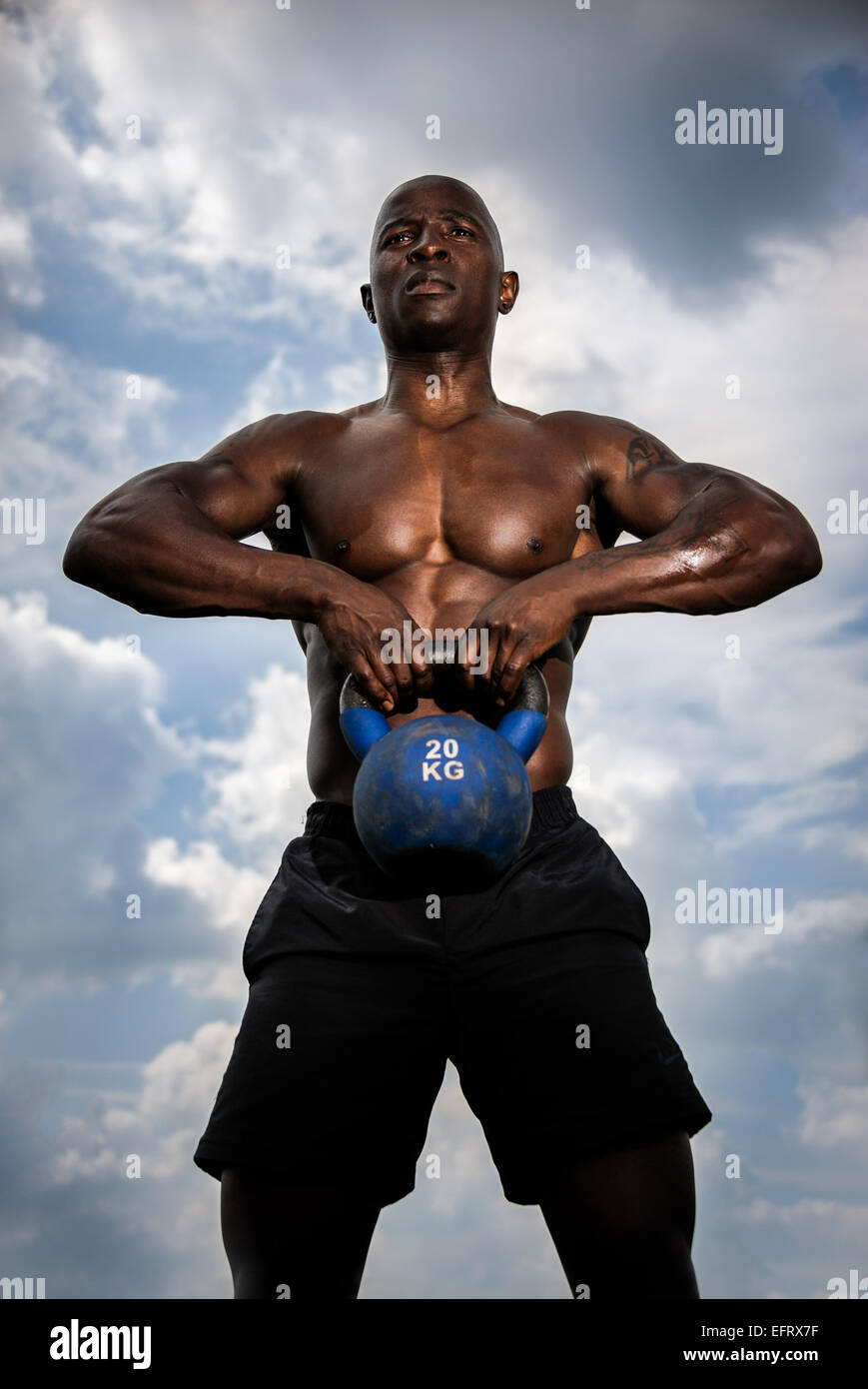 Schwarzer Rüde mit großen Kessel Glocke Gewicht Training im freien Stockfoto