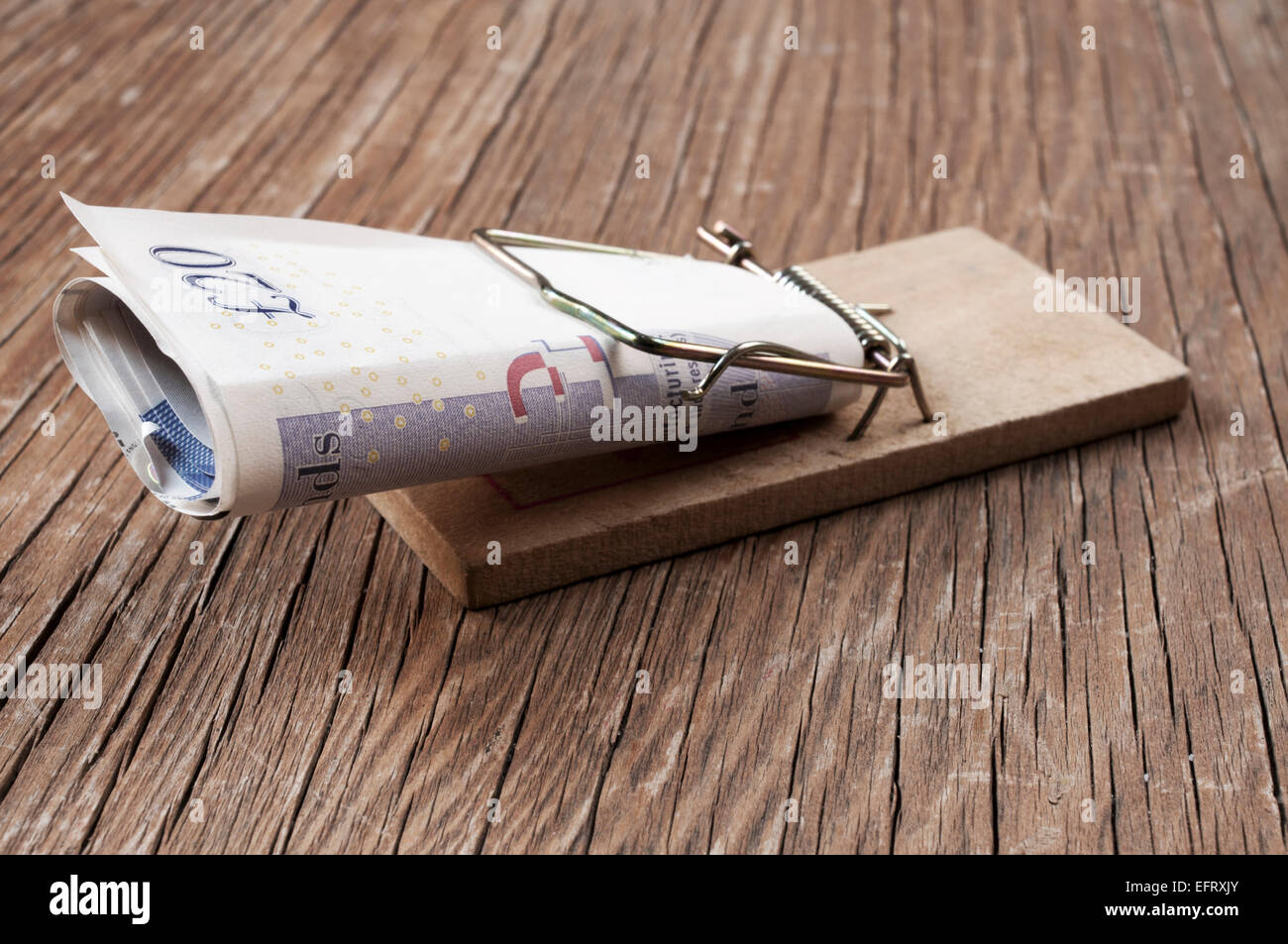 Pfund Sterling Rechnungen in einer Mausefalle auf einer rustikalen Holzoberfläche Stockfoto