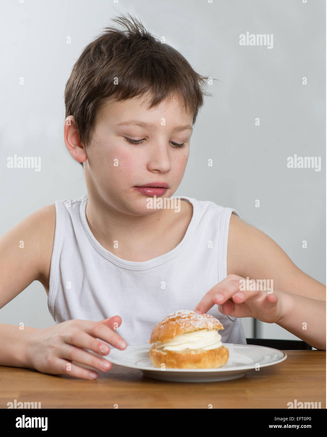 Kleiner Junge mit einem leckeren Creme Brötchen Stockfoto