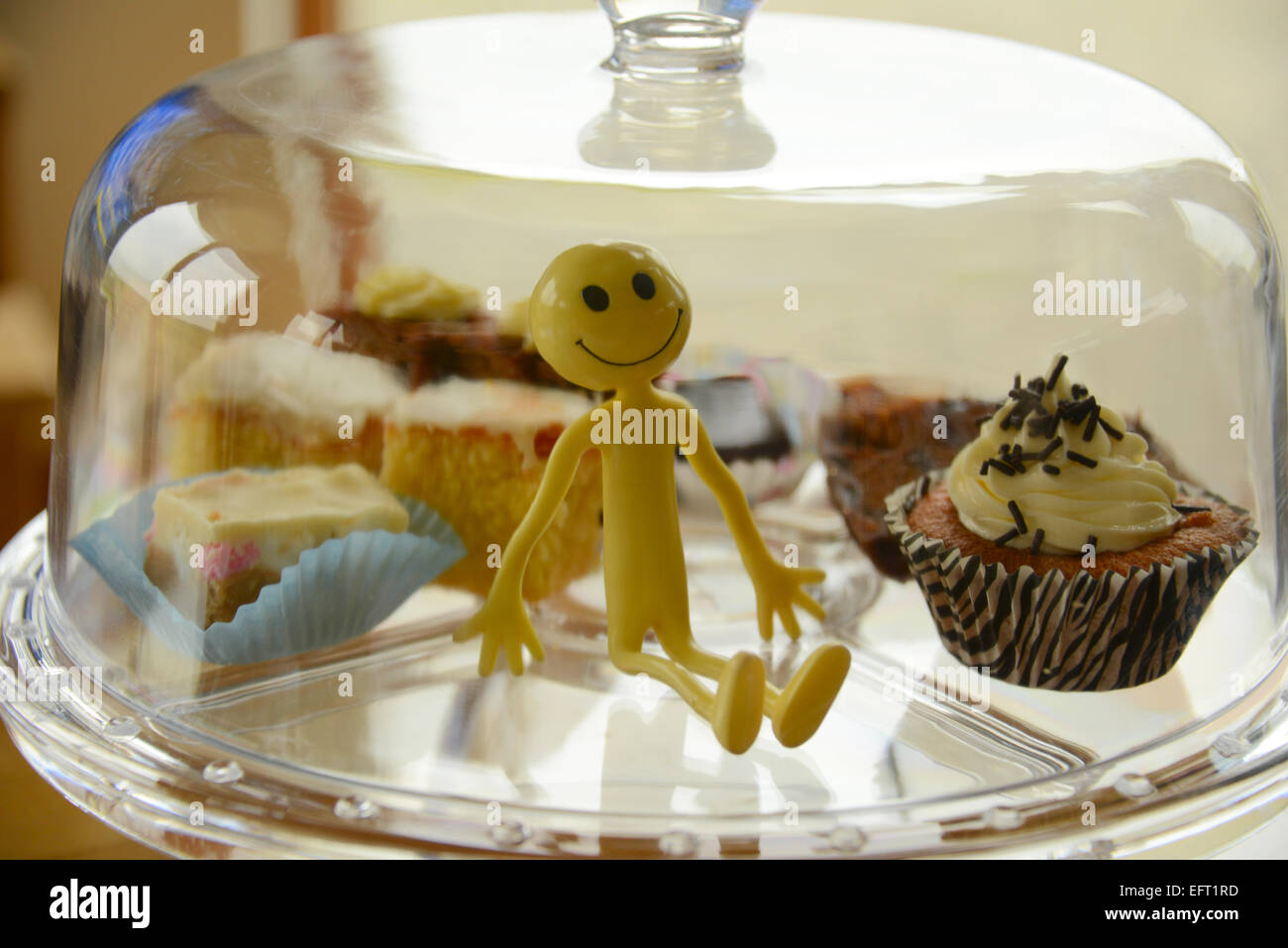 Gelber Smiley-Mann im Urlaub in den äußeren Hebriden - hat hier er glücklich in einer Glaskuppel Kuchen gefangen Stockfoto