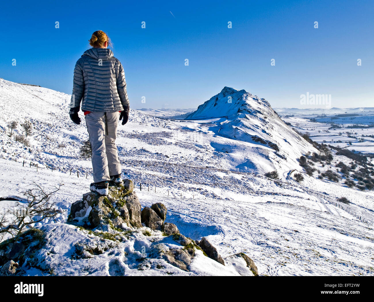 Eine weibliche Wanderer nähert sich einem Schnee Chrom Hill in der oberen Taube Tal im Peak District abgedeckt Stockfoto