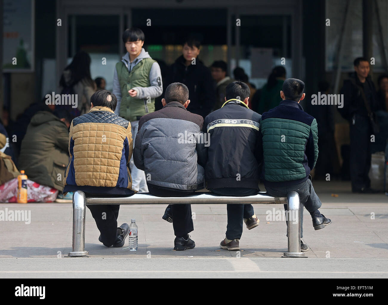 Der Provinz Hunan Changsha, China. 9. Februar 2015. Vier Männer sitzen auf einer Metallbarriere genießen Sie Sonne vor dem Eingang des Changsha Bahnhof in Changsha, der Hauptstadt der Provinz Zentral-China Hunan, 9. Februar 2015. Die 40-Tage-Reise-Raserei, bekannt als "Chunyun", die hektische Zeit rund um Spring Festival, das dieses Jahr am 19. Februar fällt, begann am 4. Februar und dauert bis 16. März. Bildnachweis: Li Ga/Xinhua/Alamy Live-Nachrichten Stockfoto