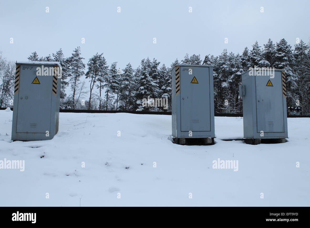 drei Metall-Box von Transformatoren bleiben auf Hügel in Wintertag Stockfoto