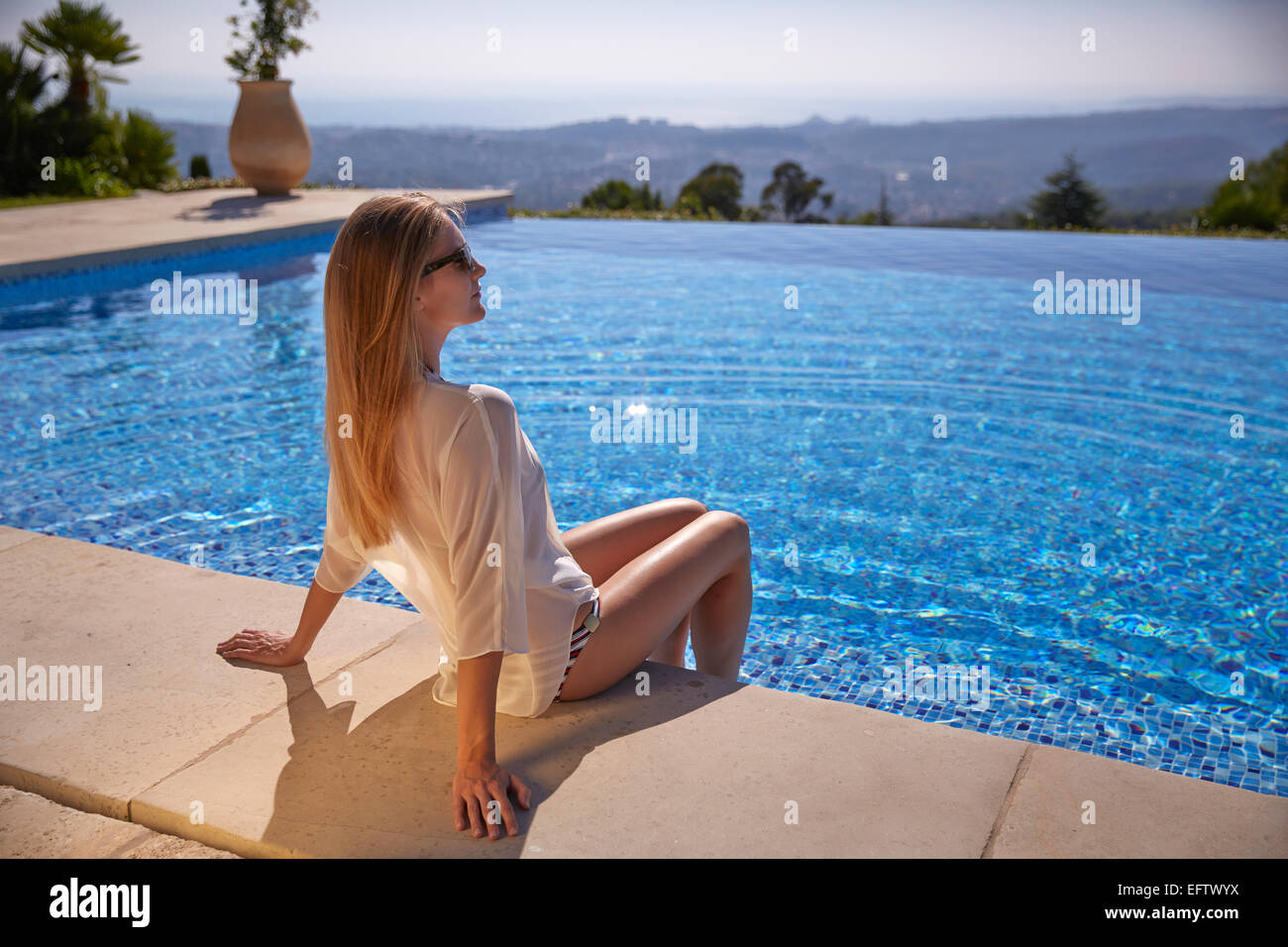 Junge Frau sitzt am Pool im Urlaub in Südfrankreich Stockfoto