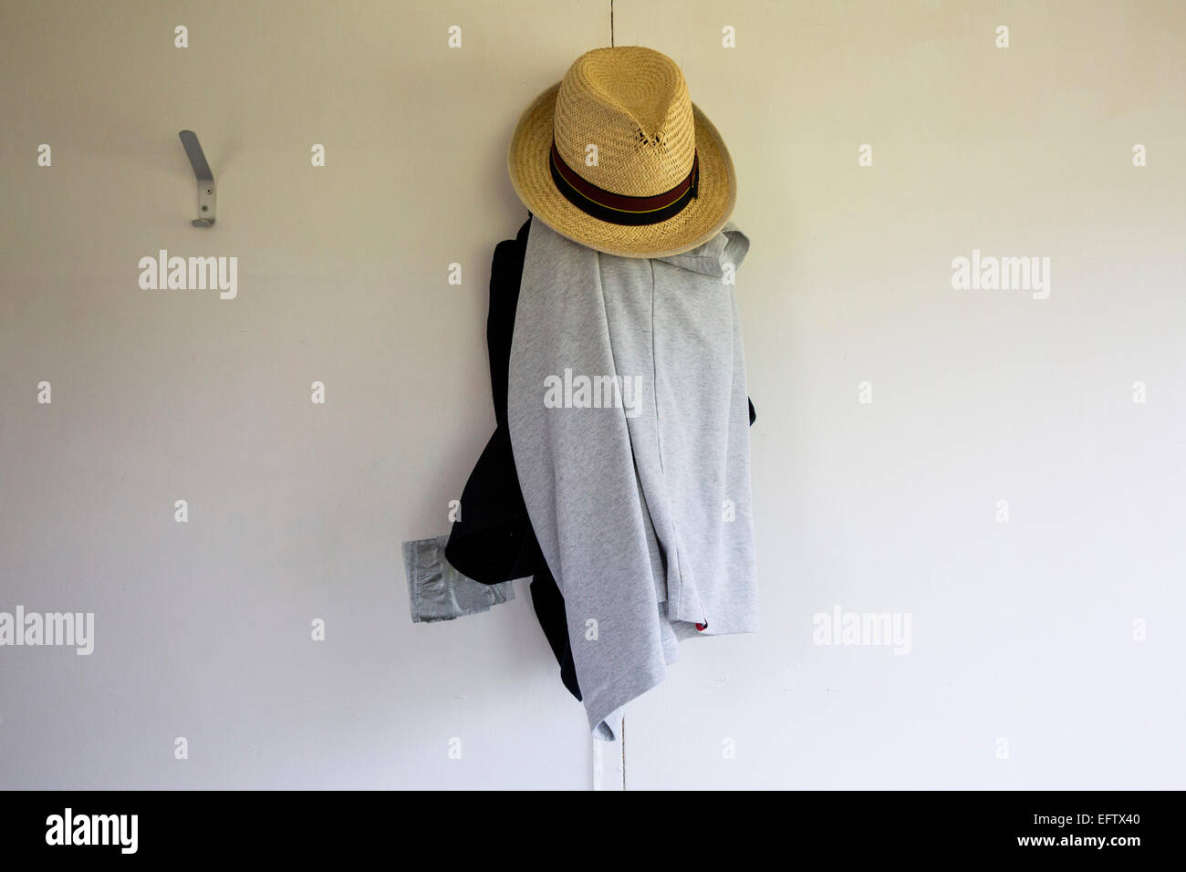 Strohhut und Kleidung hängen von Garderobe Haken Stockfoto