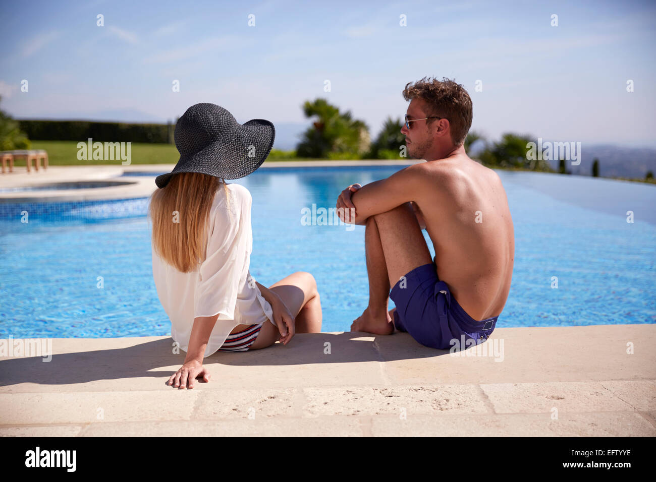 Junges Paar im Urlaub sitzt am Pool. Stockfoto