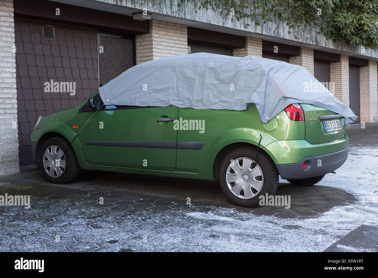 Ein geparktes Auto hat eine Abdeckung über der Windschutzscheibe und anderen Fenstern, vor Frost schützen Stockfoto