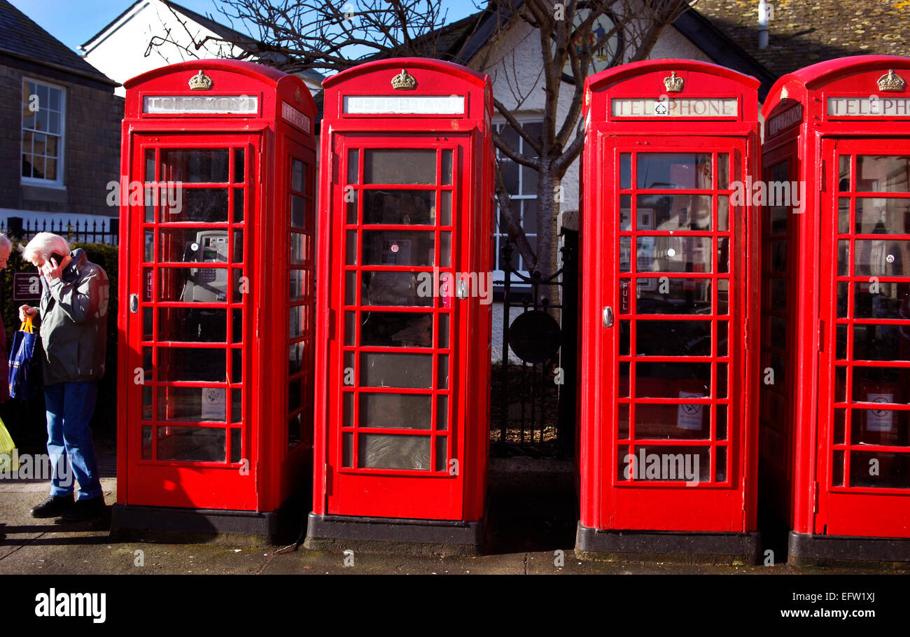 Ein Fußgänger mit einem Mobiltelefon neben traditionellen roten Telefon Call-Boxen in Truro, Cornwall. Stockfoto