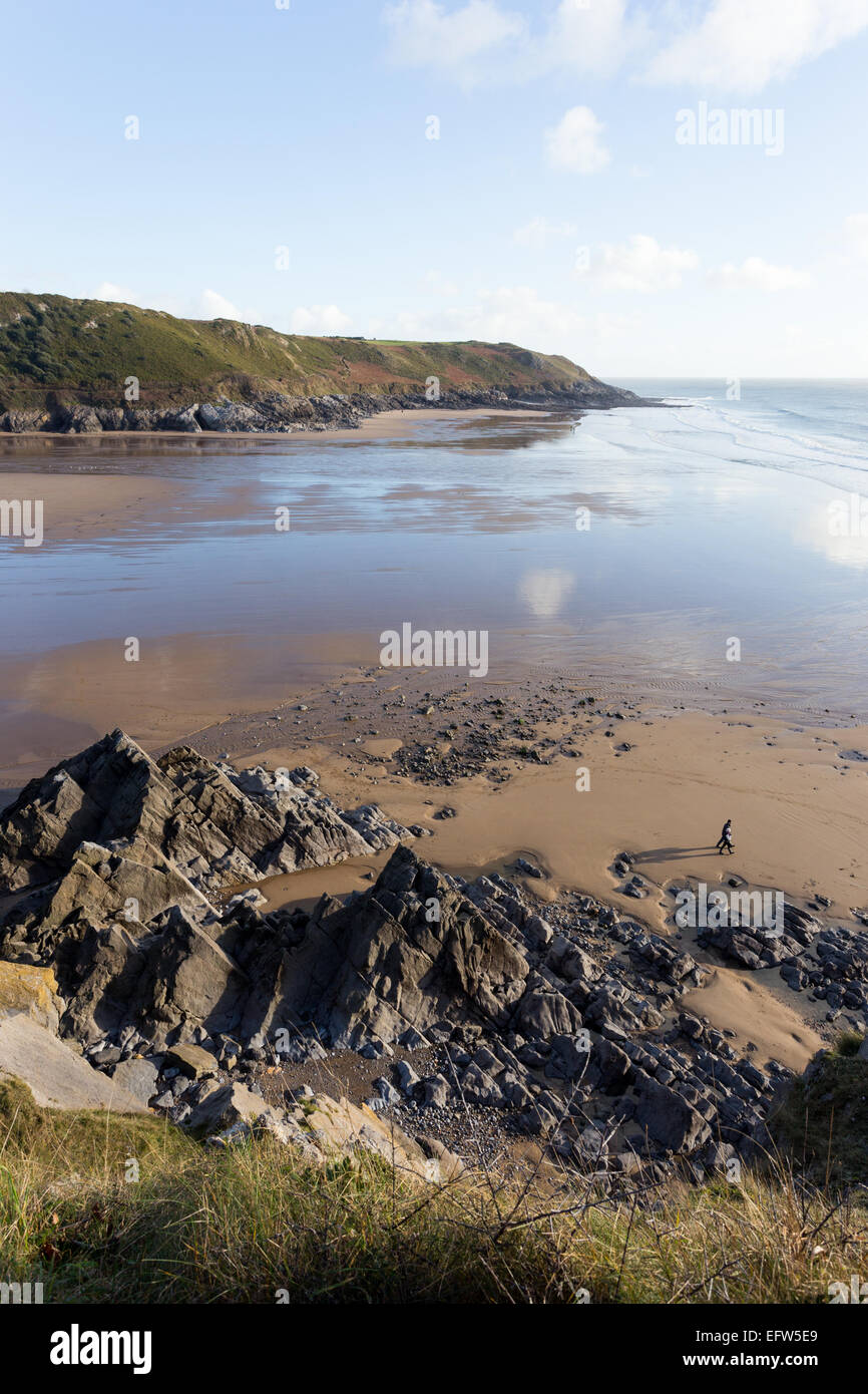 Caswell Bucht gesehen von der Clilffs über, mit riesigen Felsen Verzwergung der Figuren der zwei Wanderer Stockfoto