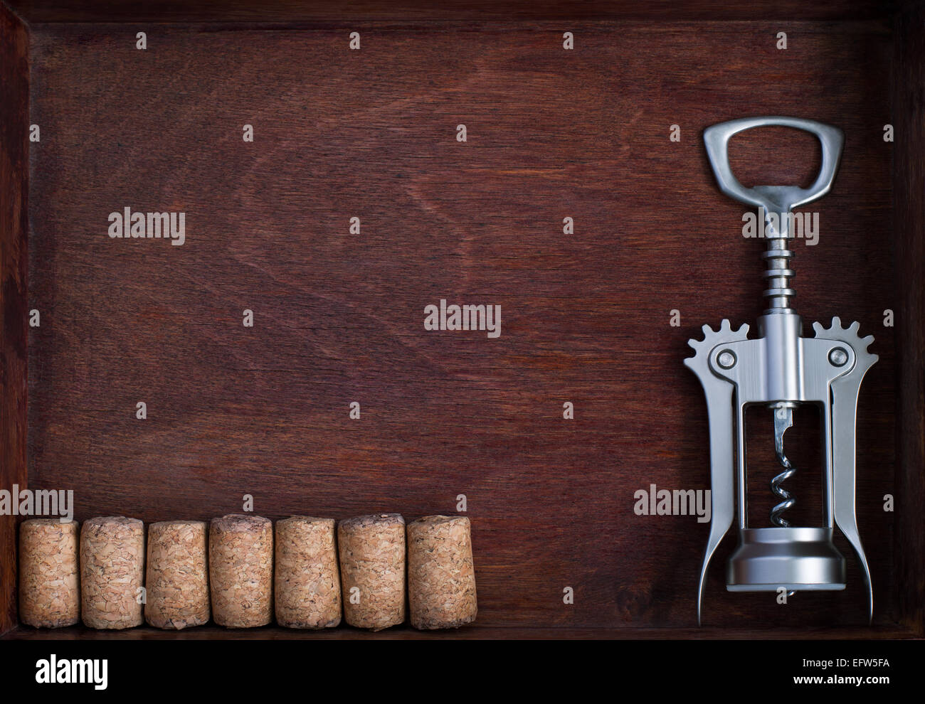 Korkenzieher und eine Reihe von identischen Weinkorken in dunklen Kasten Stockfoto