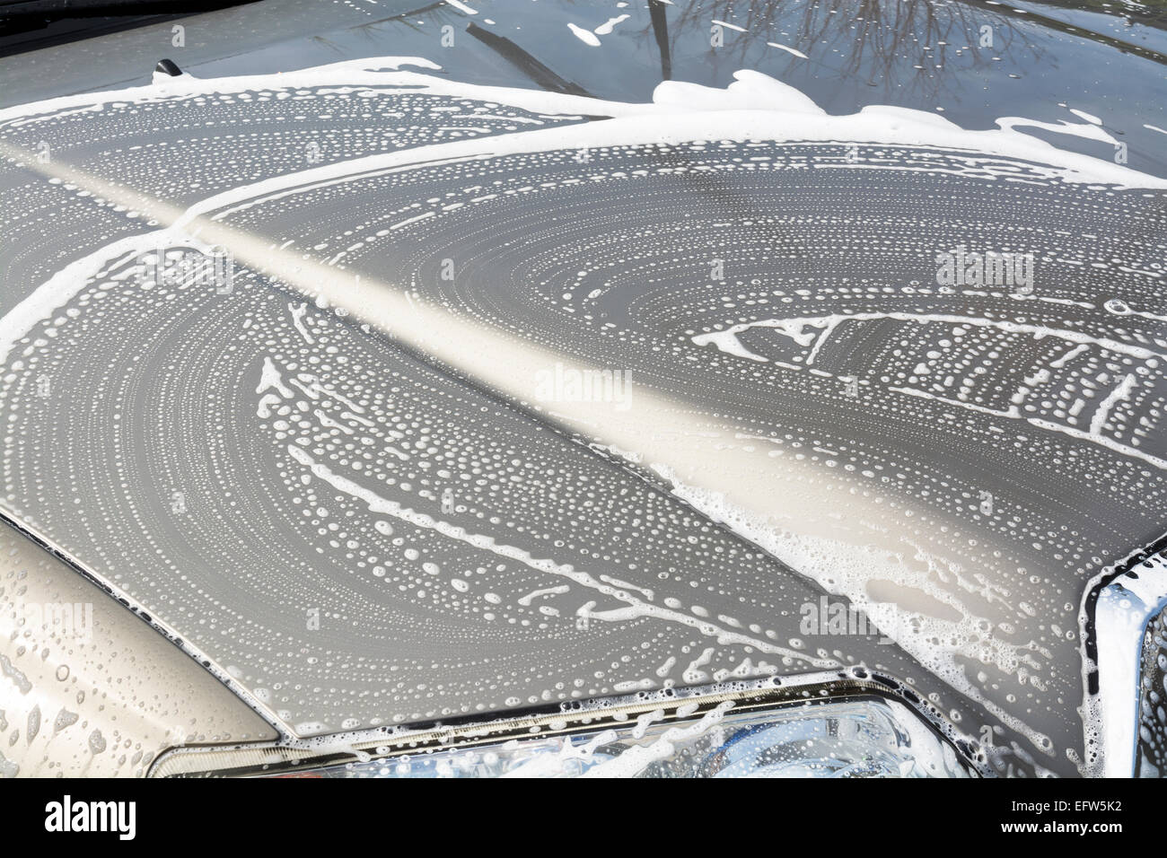 Eine seifige Automobil Kapuze mit Sud wirbelt Versandkäfigen beim Waschen ein Auto Stockfoto