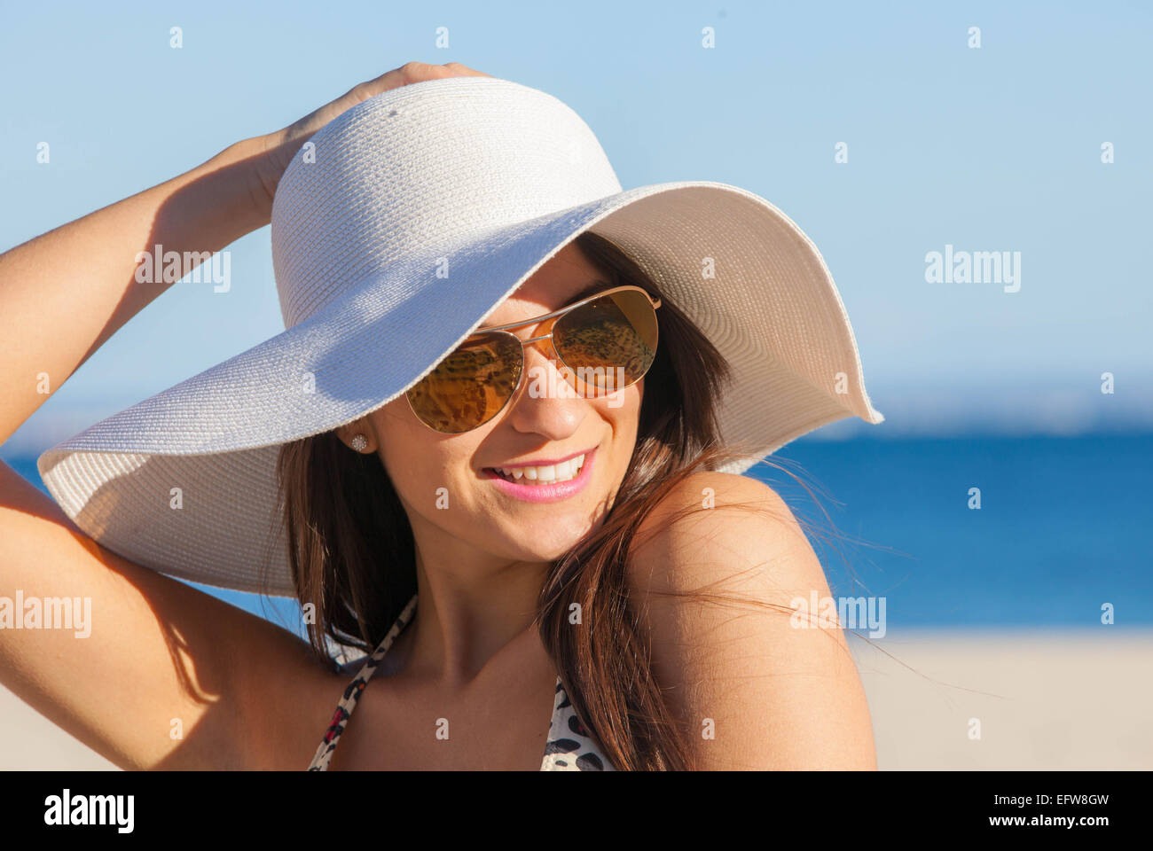 lächelnde Frau Sommer am Strand mit Sonnenbrille und Schlapphut Stockfoto
