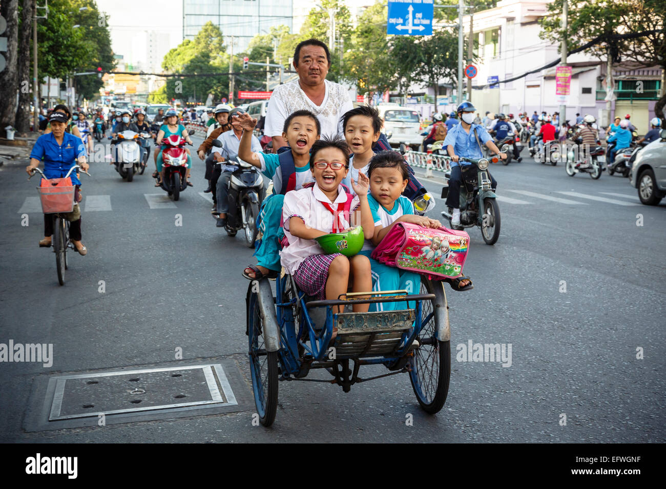 Schule Kinder reiten Fahrradrikscha auf einer belebten Straße, Ho-Chi-Minh-Stadt (Saigon), Vietnam. Stockfoto