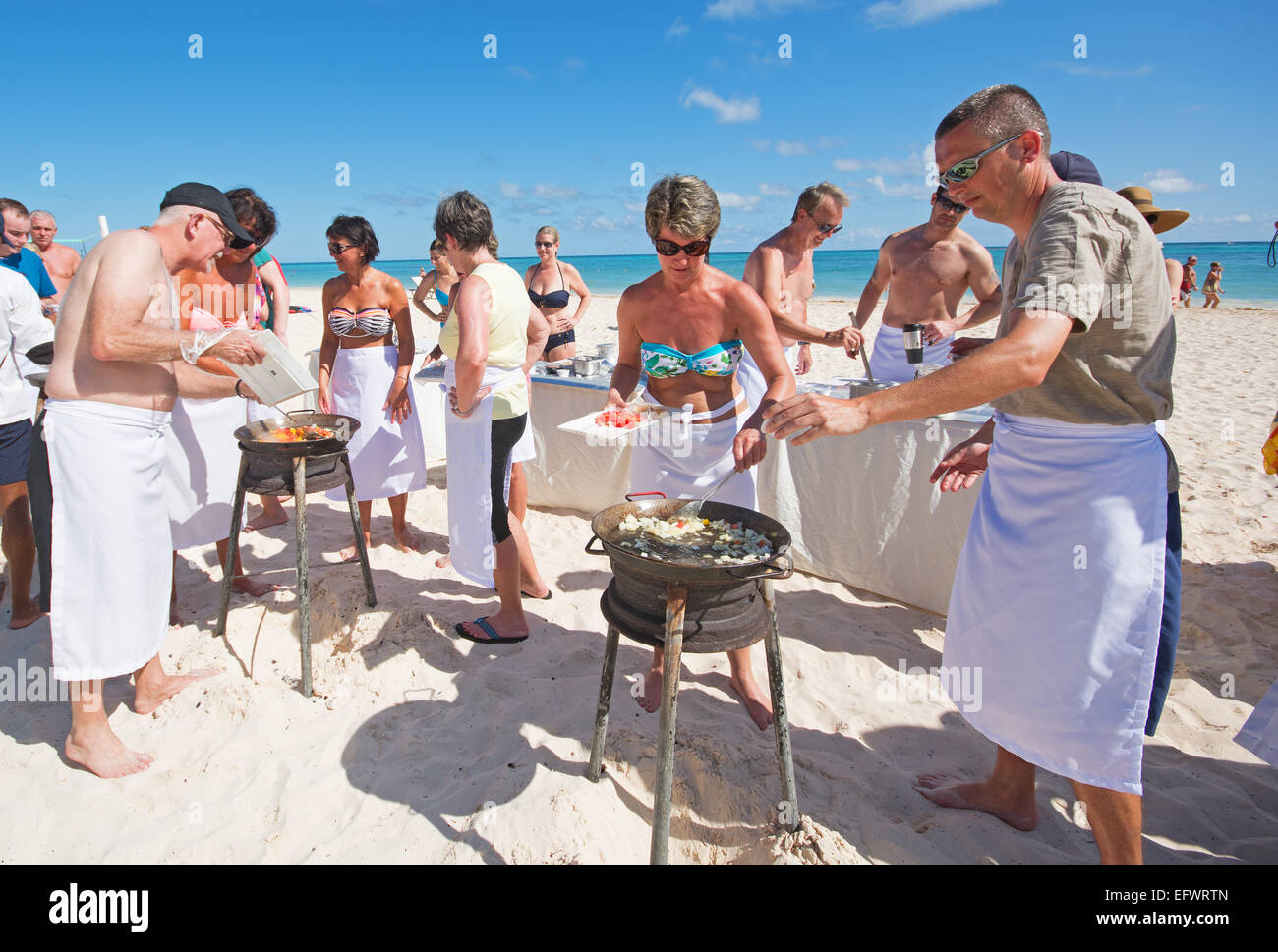 Dominikanische Republik. Urlauber, die im Wettbewerb mit einer Paella Kochwettbewerb am Strand von Punta Cana. 2015. Stockfoto