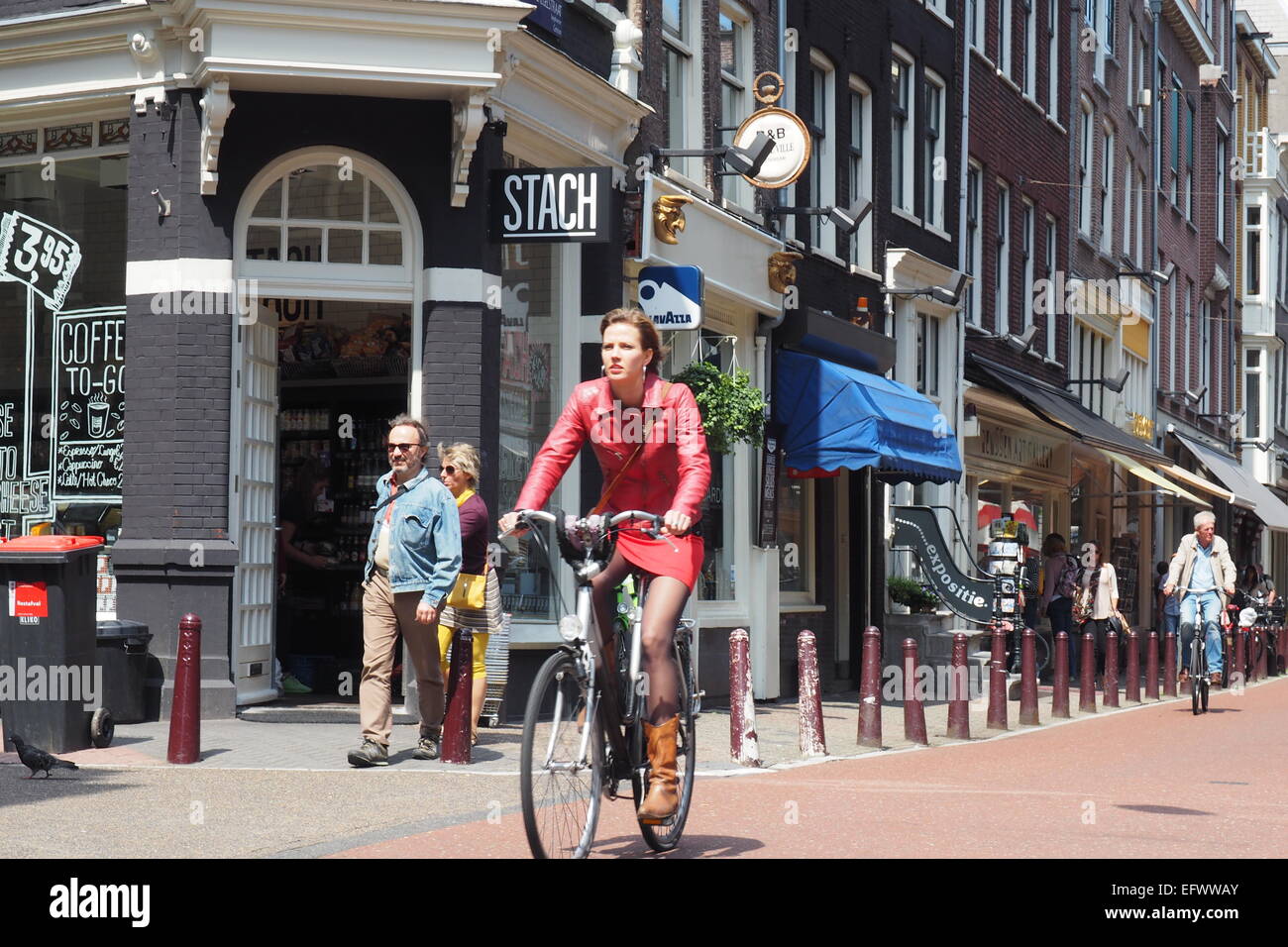 Eine Frau im roten Outfit Radfahren in Amsterdam. Stockfoto